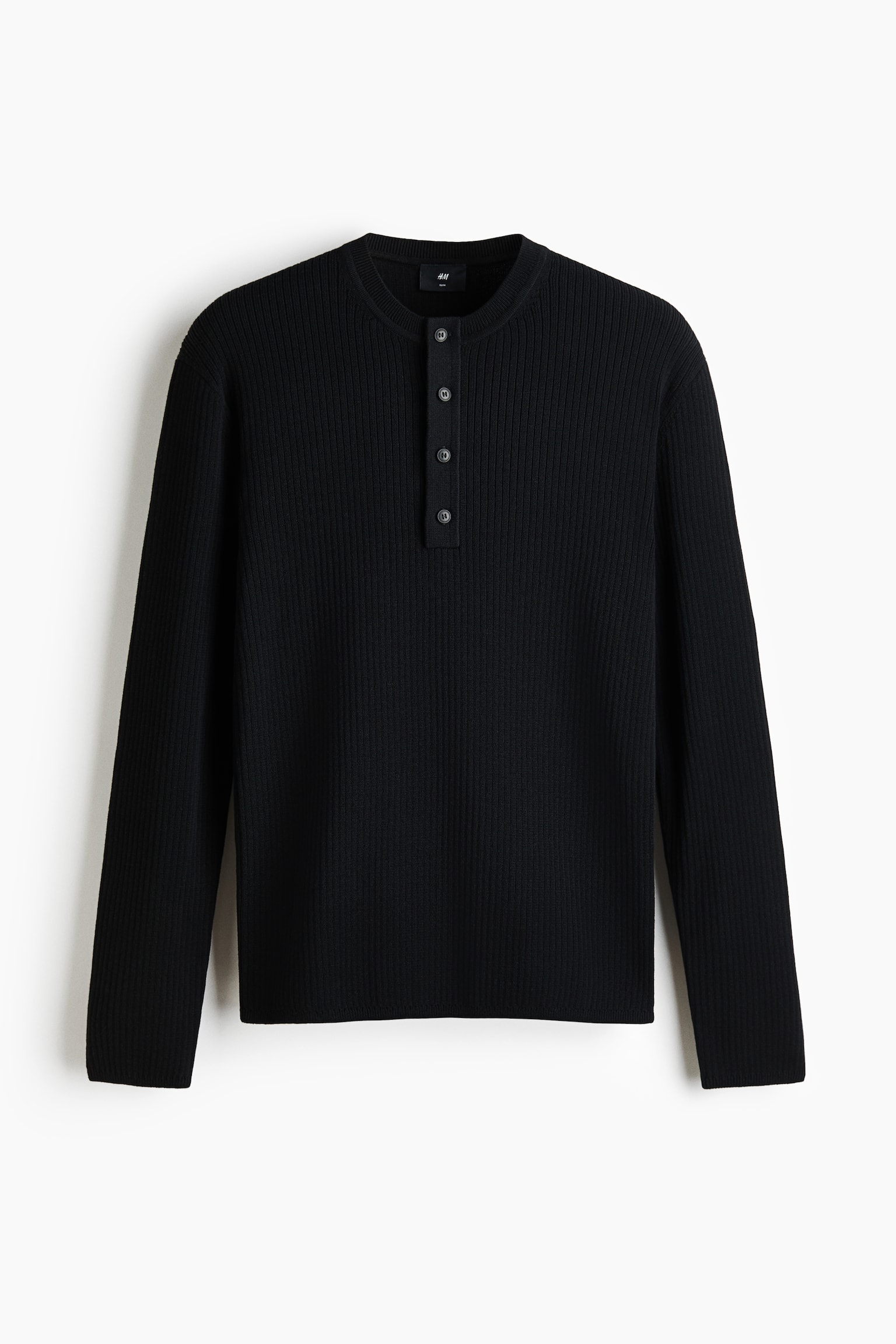 Una blusa negra acanalada estilo Henley está de frente, con cuello redondo y una tapeta de cuatro botones. Está diseñada con mangas largas y un dobladillo recto. - 1