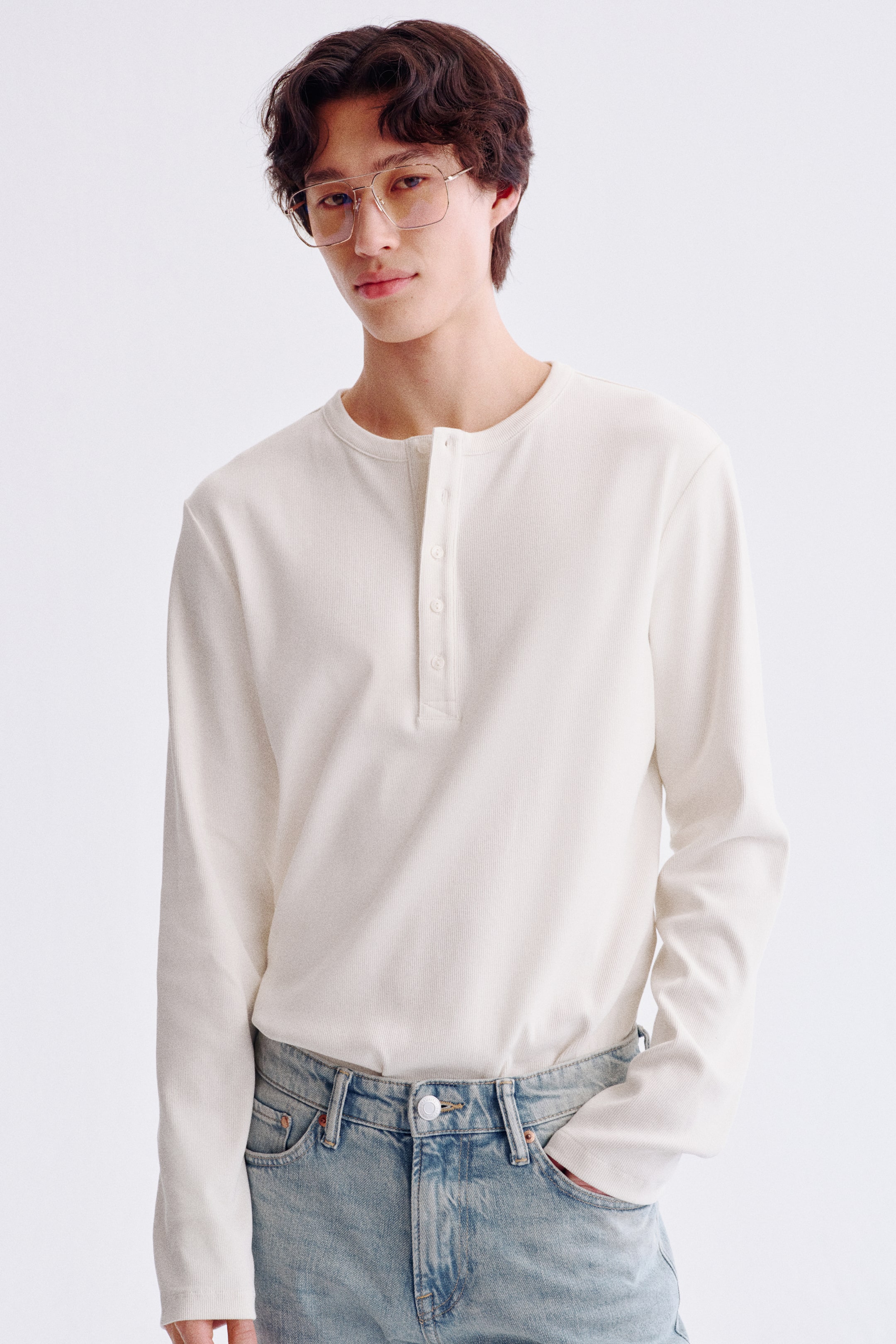 Visa större bild: En benvit långärmad Henley-tröja visas framifrån, med en rund halsringning och en femknappslå. Tyget har en fin ribbad struktur.