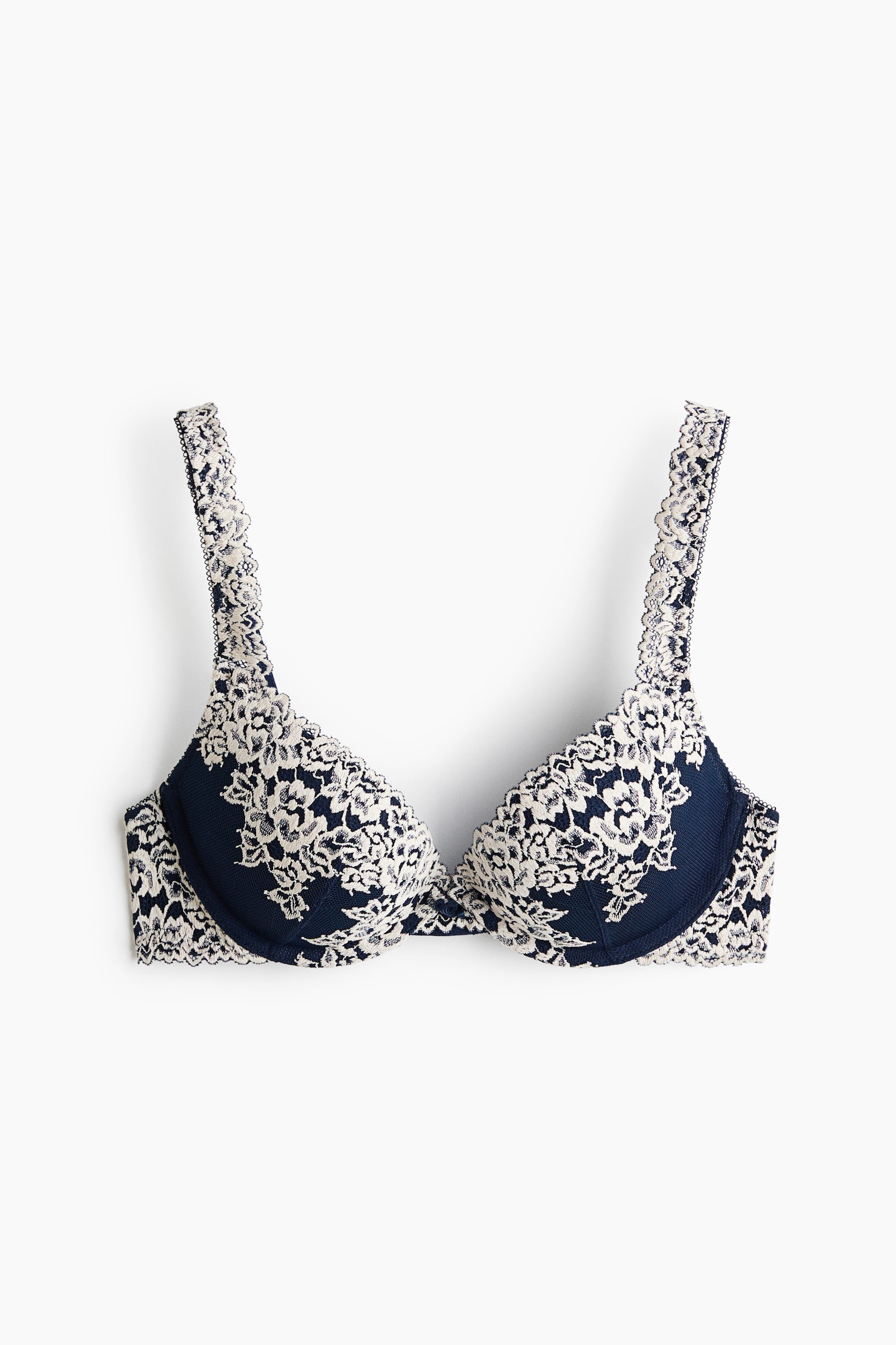 A front view of a dark blue push-up bra featuring underwired, padded cups overlaid with intricate cream-coloured floral lace. The lace extends up the shoulder straps and along the band, creating delicate scalloped edges.