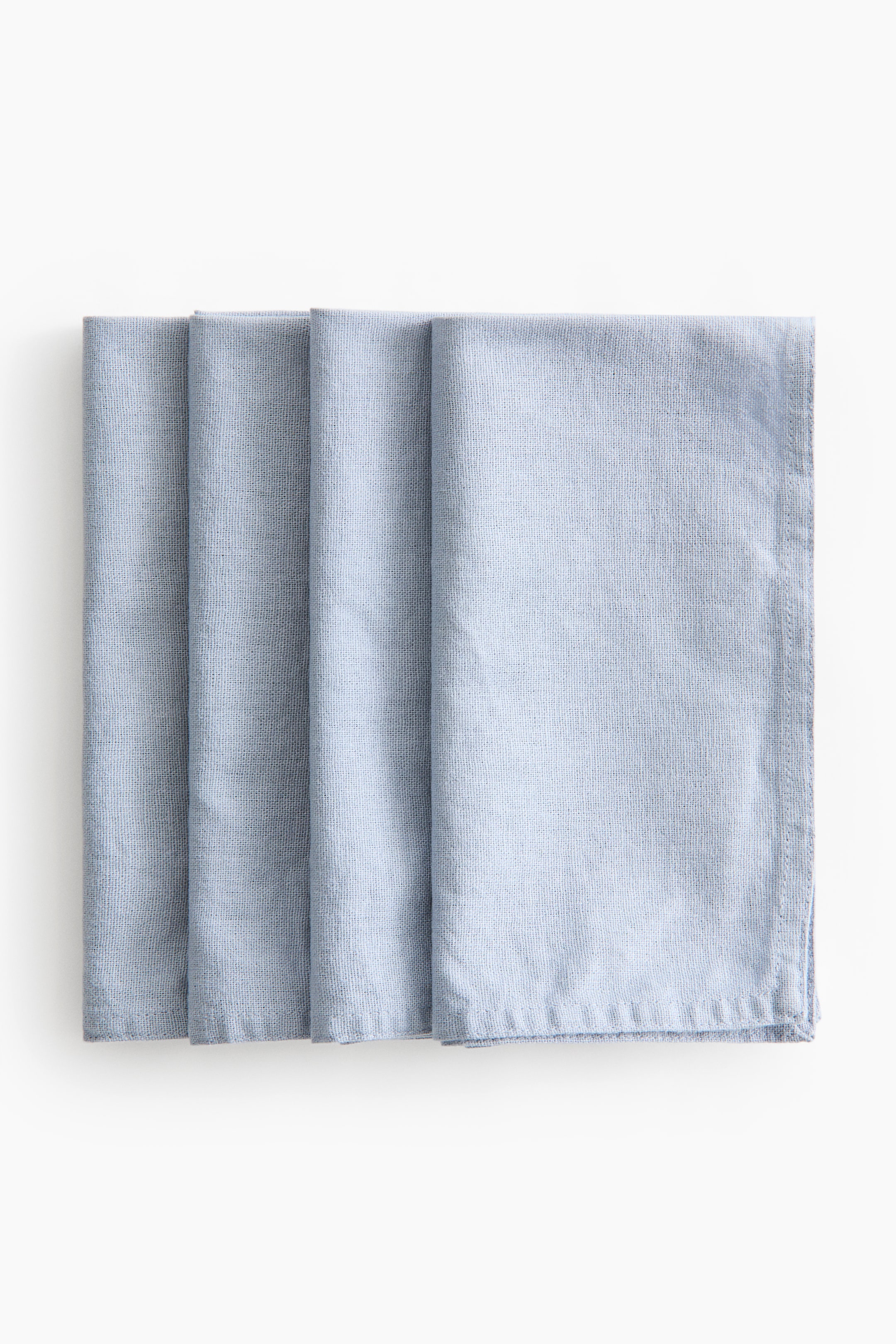 View larger image: Four light blue napkins made from a textured linen and cotton blend are overlapped in a row, showing their rectangular folds and stitched hems.
