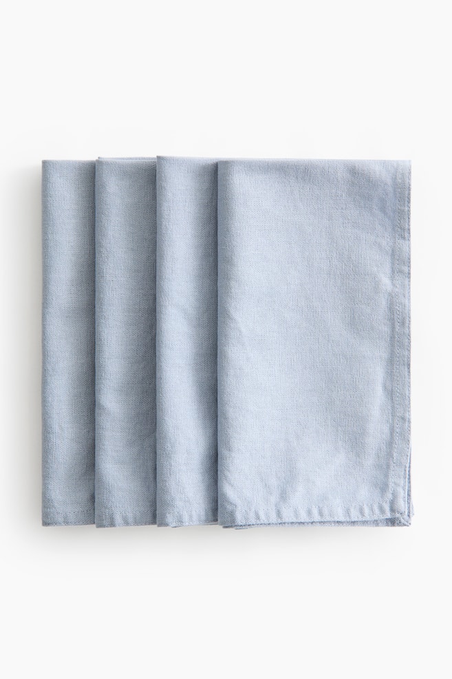 Four light blue napkins featuring a textured linen and cotton blend are overlapping in a row, displaying their rectangular folds and stitched hems. - 1