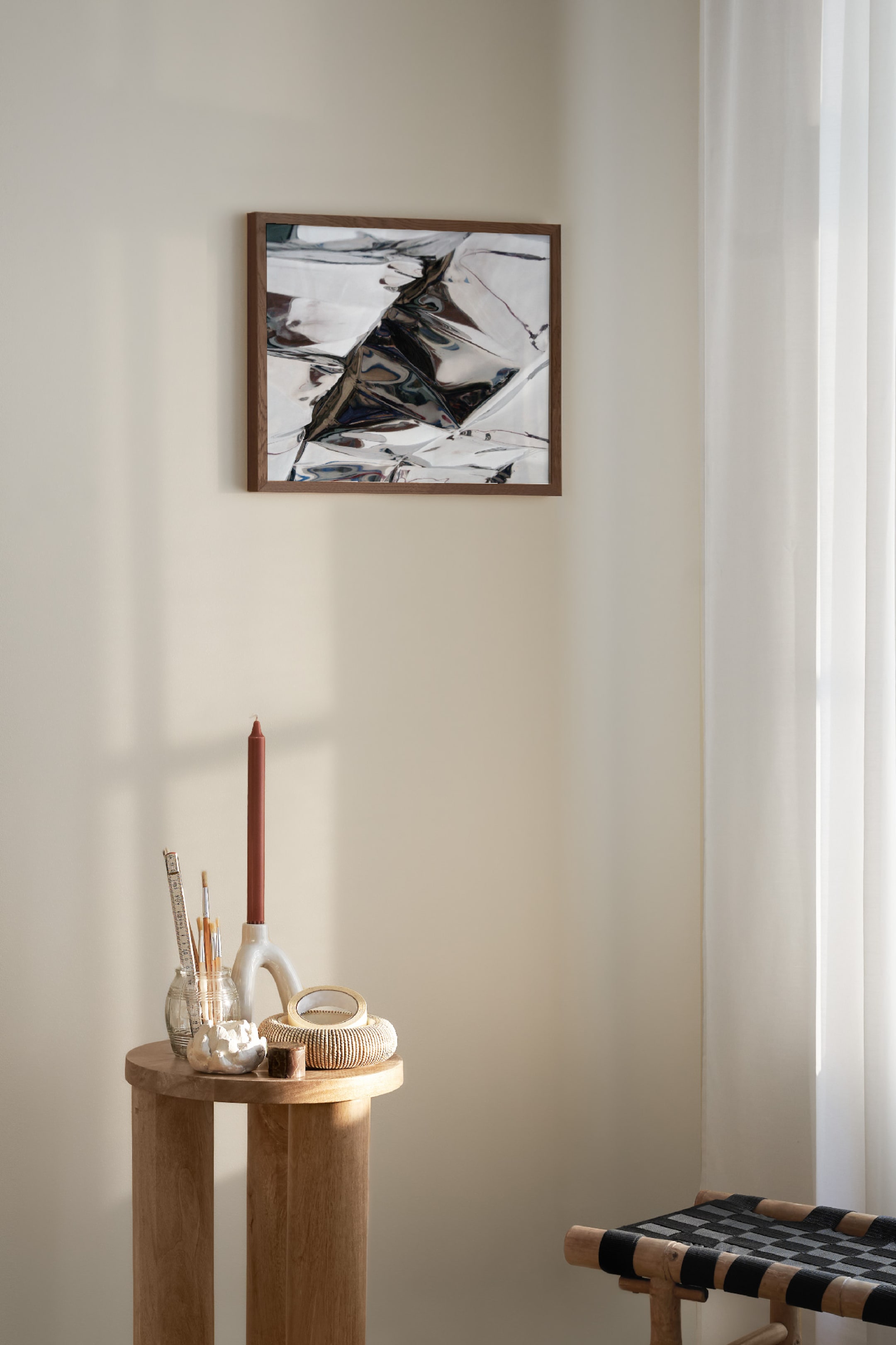 View larger image: A framed artwork is hanging on a wall, featuring a dark brown rectangular frame with a thin border. Inside, a reflective metallic artwork displays crinkled surfaces and abstract reflections in silver, grey and black tones.