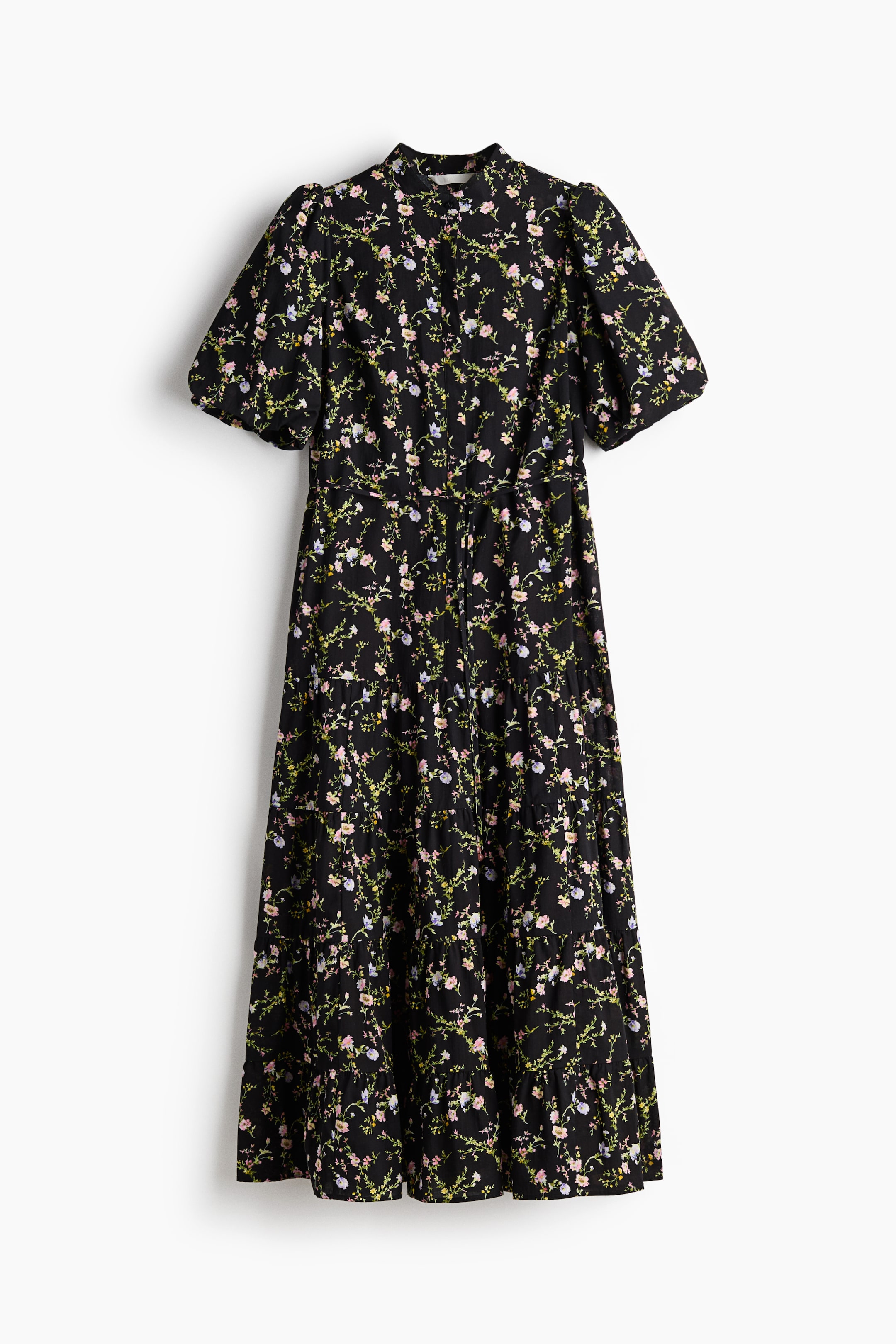 Ver imagen más grande: FRENTE: Un vestido hasta el tobillo muestra un tejido negro con un pequeño estampado floral, con un cuello tipo banda, botones ocultos en la parte superior y mangas cortas abullonadas. Un cinturón estrecho ajusta la cintura, y la falda acampanada está diseñada con volantes recogidos.