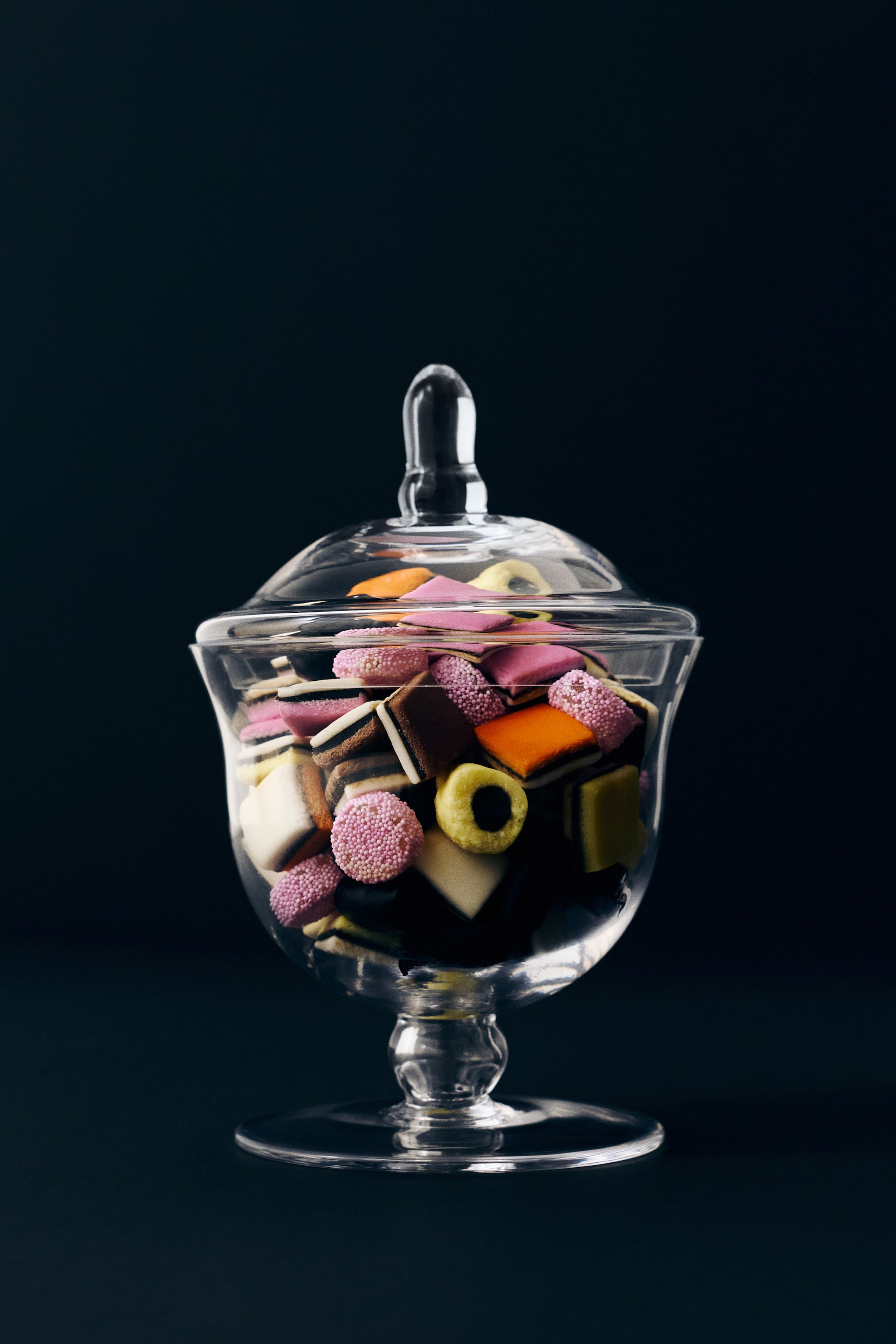Visualizza l'immagine ingrandita: Un barattolo di vetro con piede, con bordo leggermente svasato e coperchio con pomello allungato, è posizionato frontalmente e contiene un assortimento di caramelle liquorice allsorts colorate. Il barattolo in vetro trasparente mostra il suo contenuto attraverso il corpo trasparente, con il coperchio abbinato appoggiato sopra.