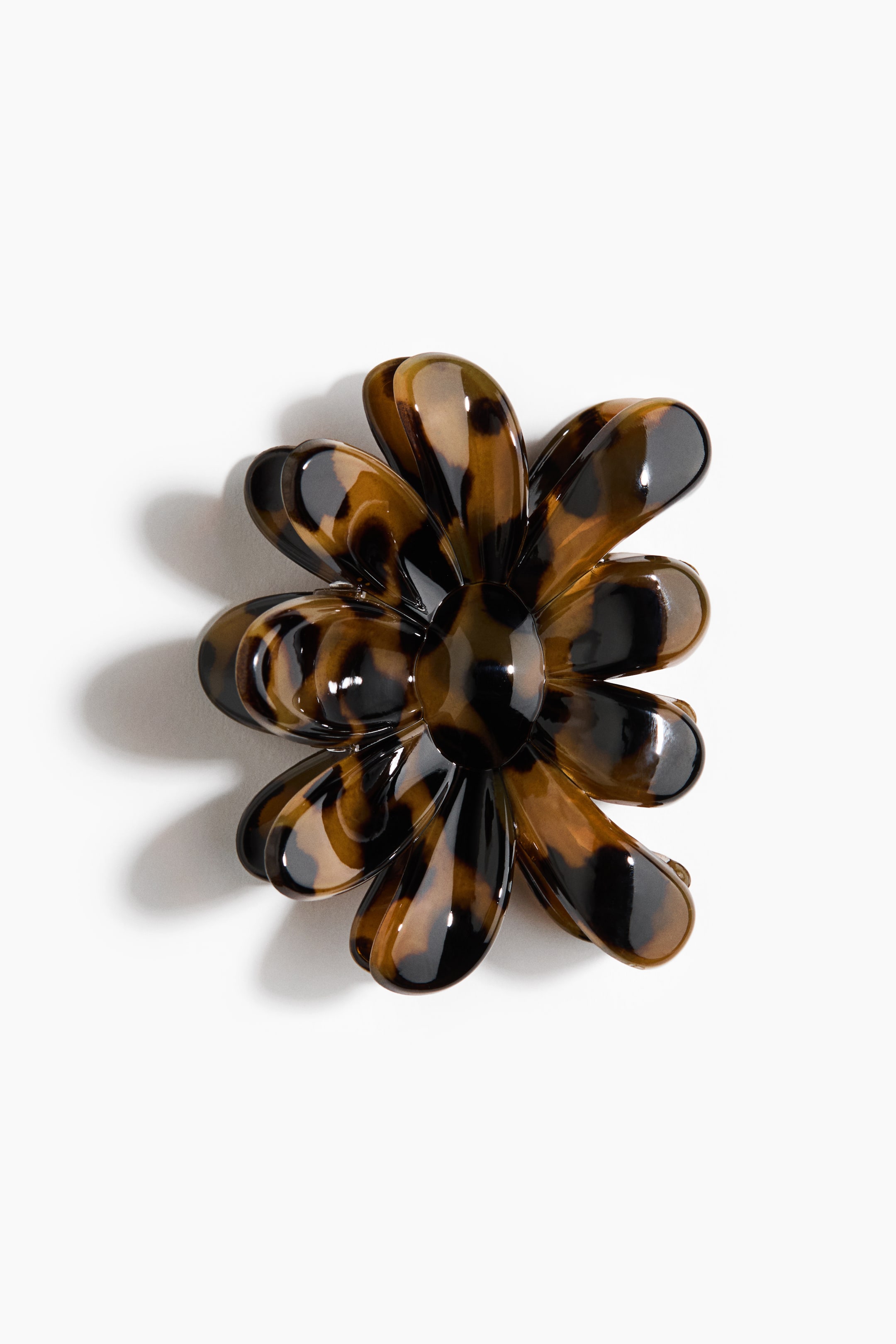 View larger image: A flower-shaped hair clip is displaying its front, featuring a glossy tortoiseshell pattern in brown and black. It is featuring multiple rounded petals.