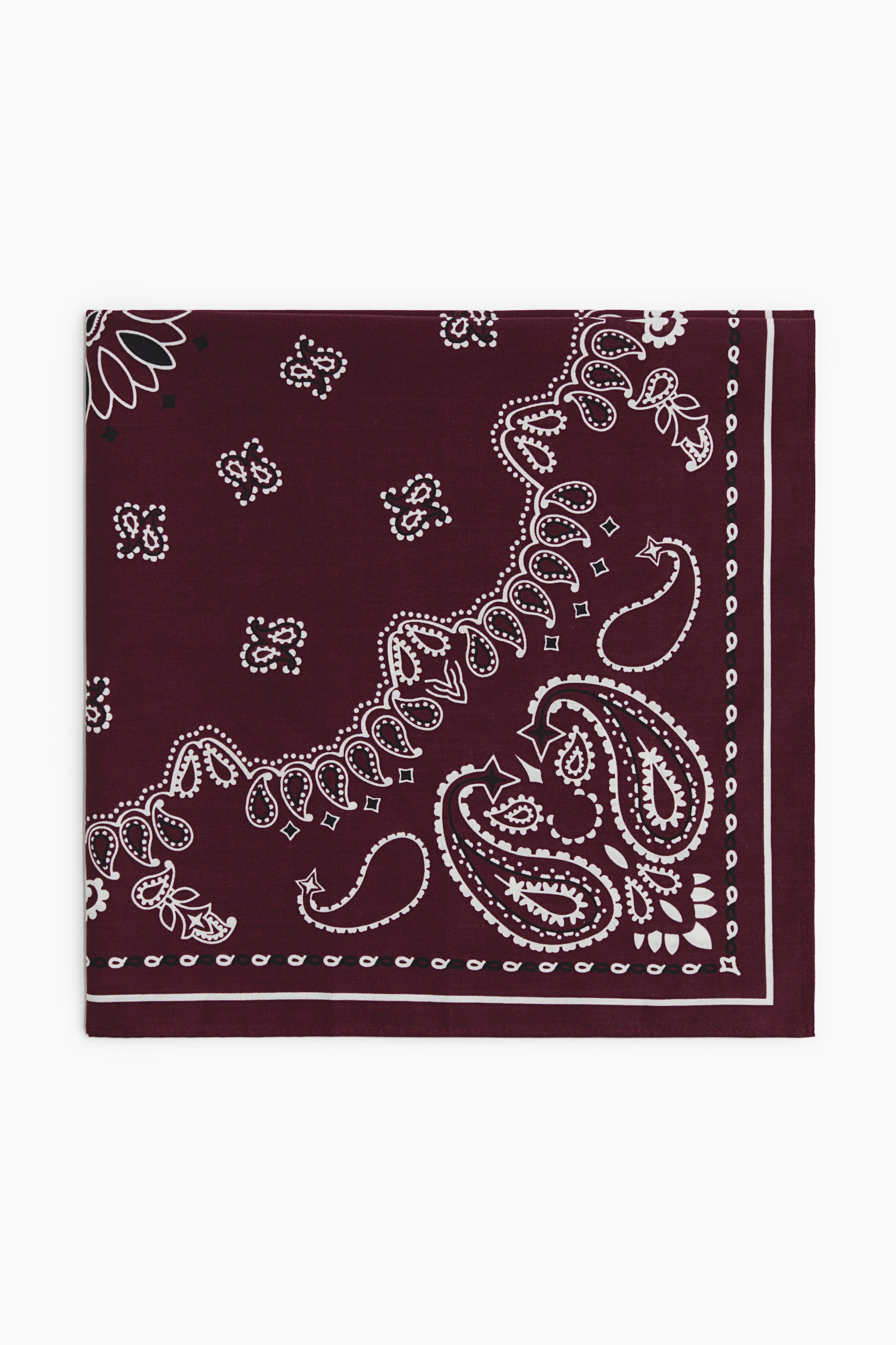 Büyük resmi görüntüle: Bandana, beyaz ve siyah paisley desenine sahip koyu kırmızı bir zemin rengi sergiliyor. Alt sağ köşede büyük bir paisley motifi bulunuyor; etrafı daha küçük, serpiştirilmiş motiflerle çevrili ve alt ile sağ kenarlarda desenli bir bordür yer alıyor.