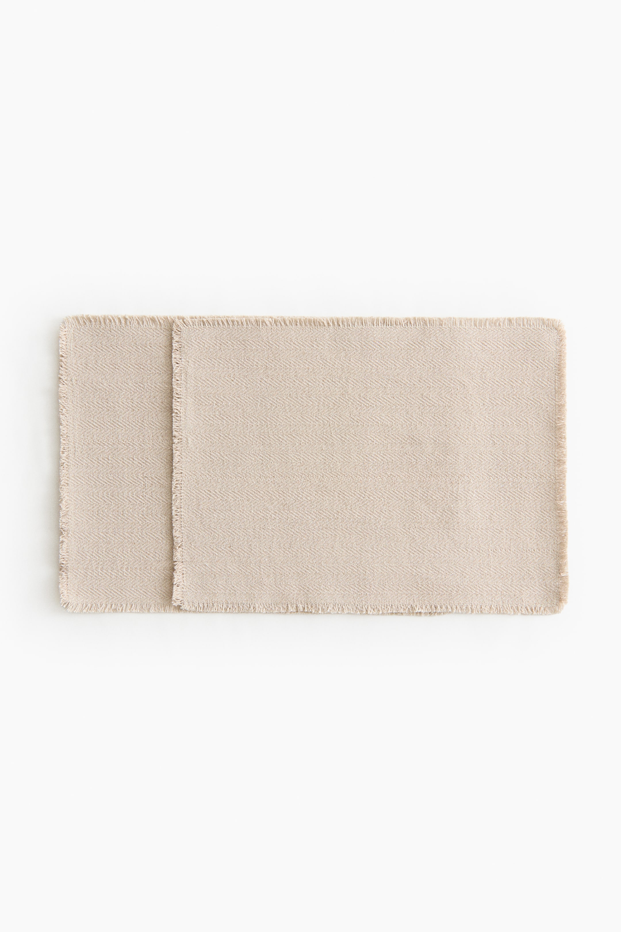 View larger image: Two rectangular fabric pieces display a light beige colour with a herringbone weave. They slightly overlap along one long edge, and all visible edges have a frayed finish.