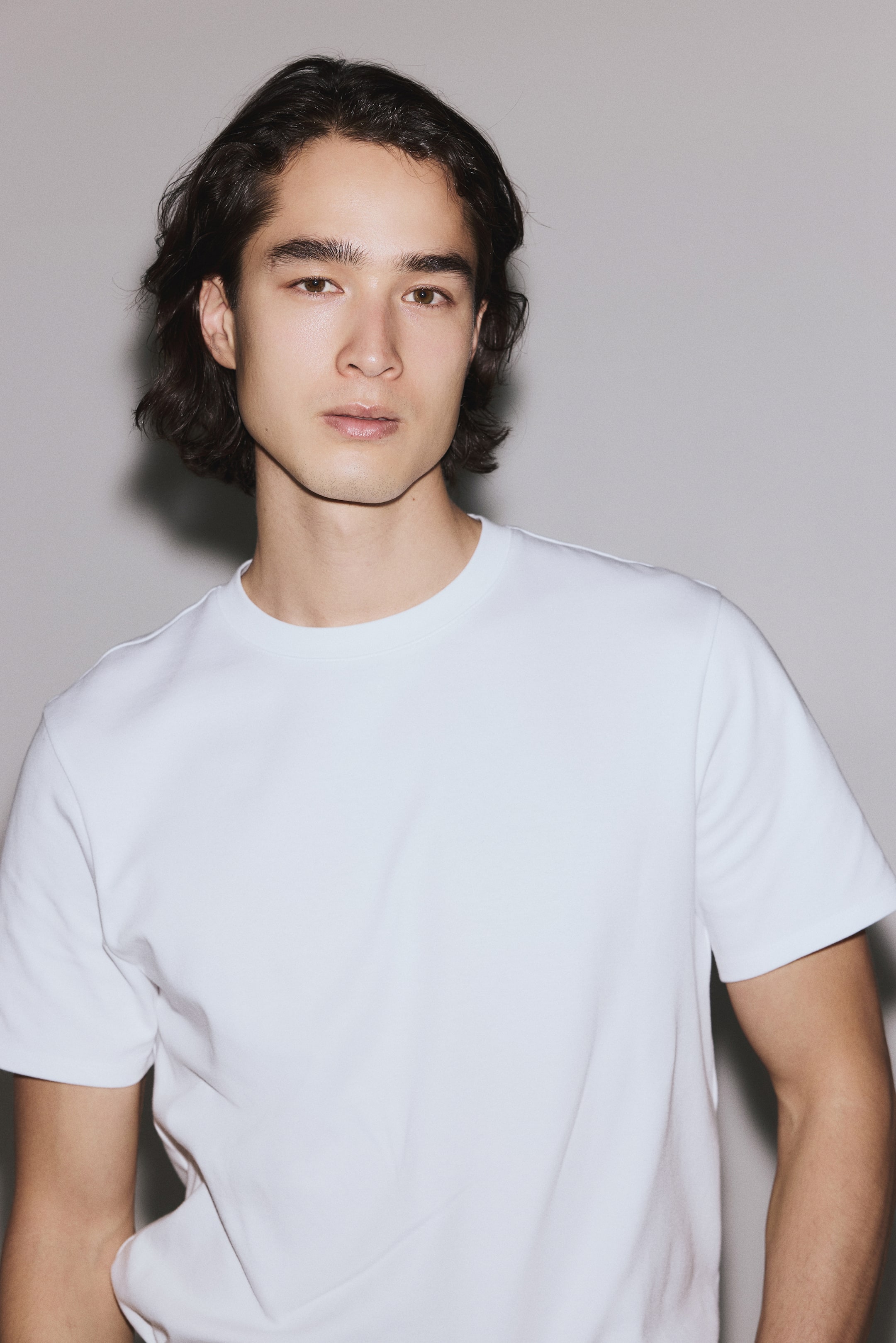 View larger image: A white T-shirt features a crew neck and short sleeves, with the front of the garment facing forward. It displays a smooth, plain texture.