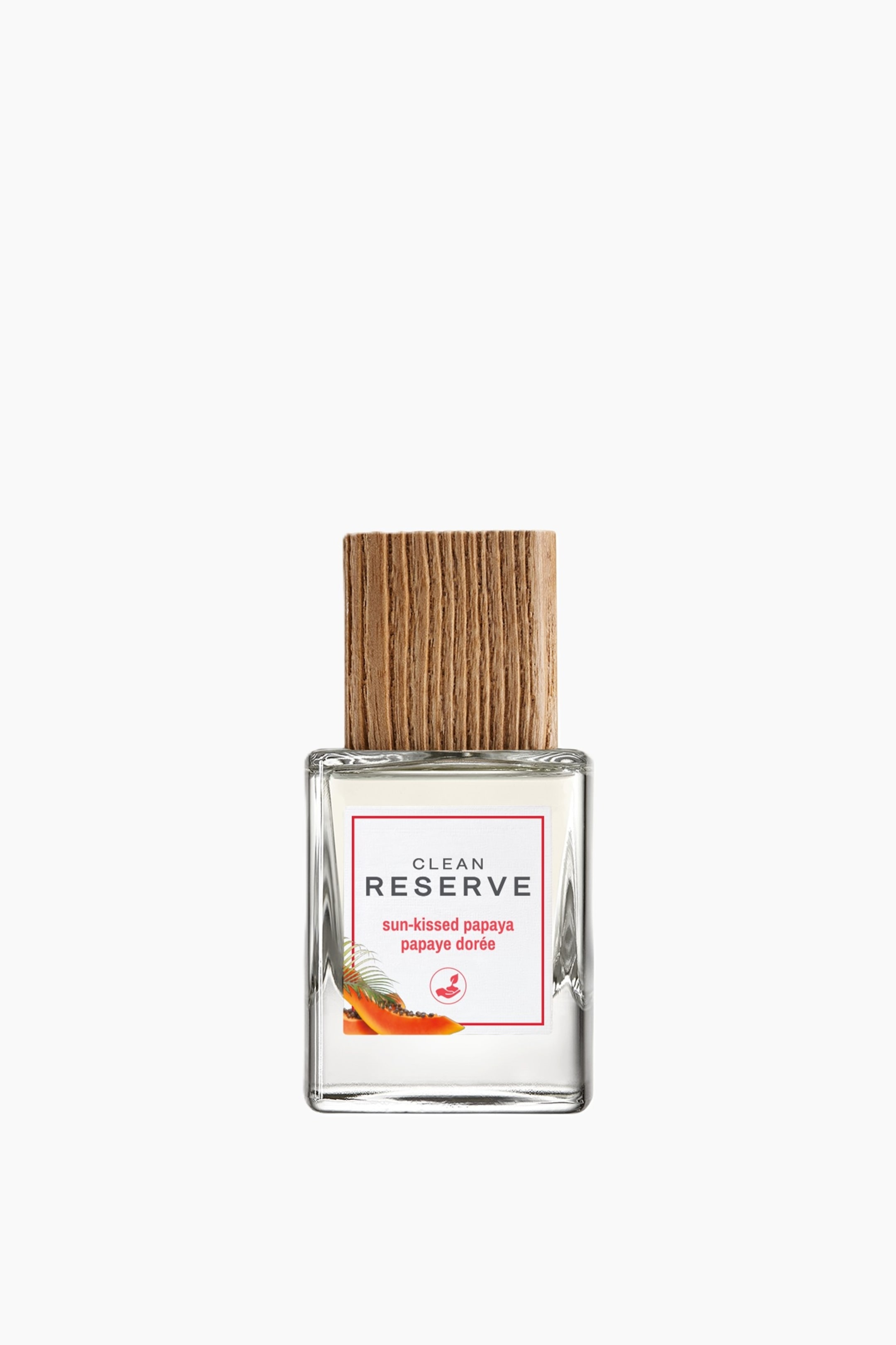 Visa större bild: En frontvy visar en rektangulär, transparent parfymflaska i glas med ett stort, texturerat trälock med vertikal ådring. Den vita etiketten på framsidan visar texten "CLEAN RESERVE sun-kissed papaya papaye dor�e" i röda och svarta bokstäver, tillsammans med en liten illustration av en uppskuren papaya.