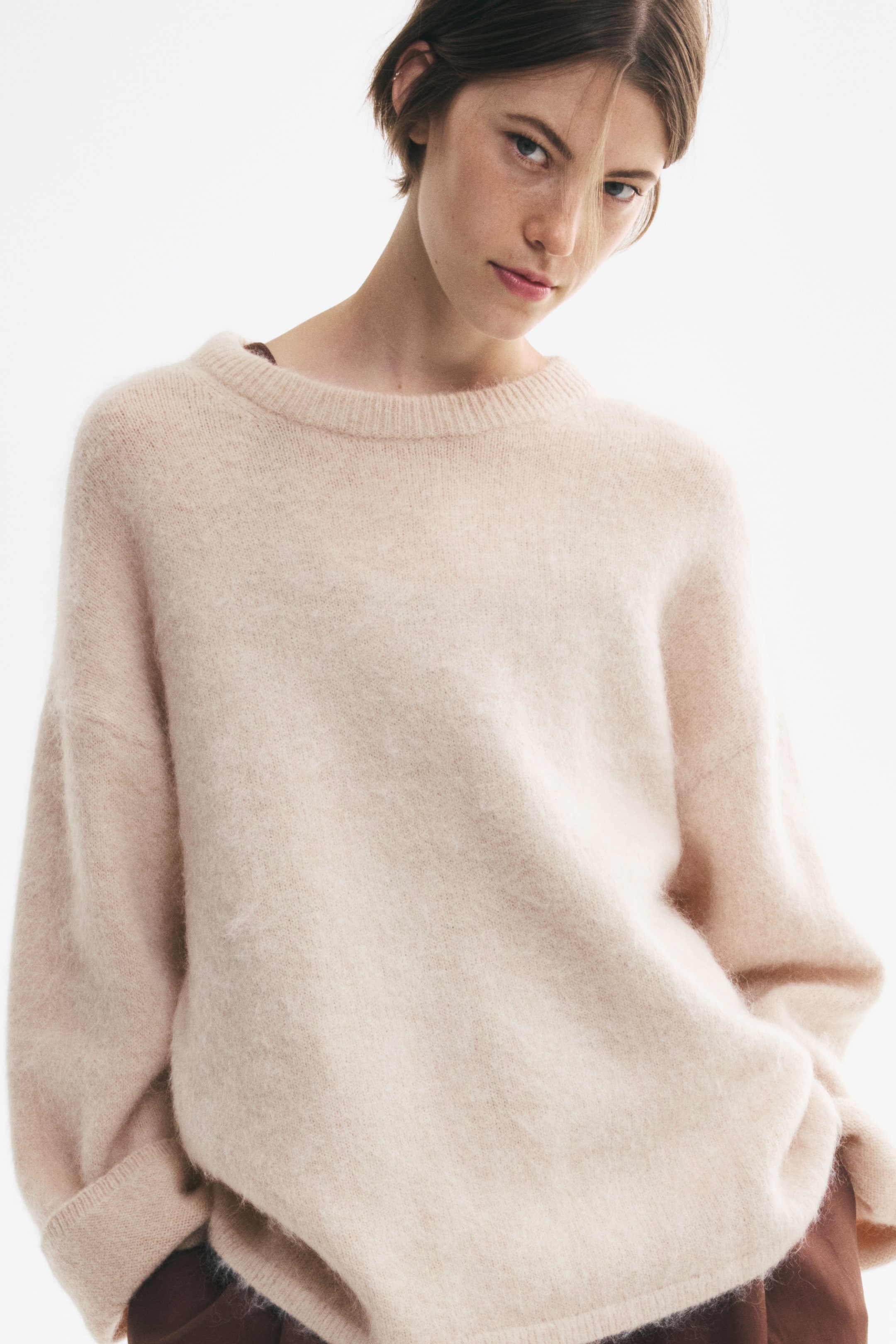 Agrandir l'image: Un pull en maille oversize beige clair est présenté de face, avec une texture duveteuse, des épaules tombantes et des manches longues à larges poignets côtelés. Le pull présente un col ras du cou côtelé et un ourlet côtelé.