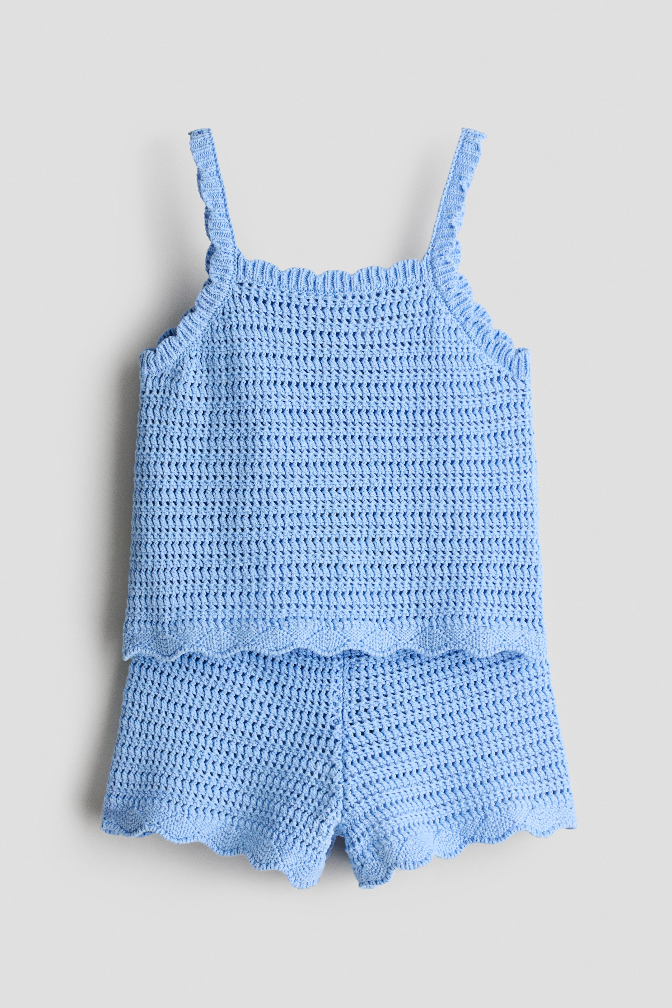 View larger image: A light blue crochet two-piece set is presented from the front, featuring a camisole-style top and matching shorts. Both pieces showcase an openwork knit pattern with scalloped edges on the straps, neckline, top hem, and short leg openings.