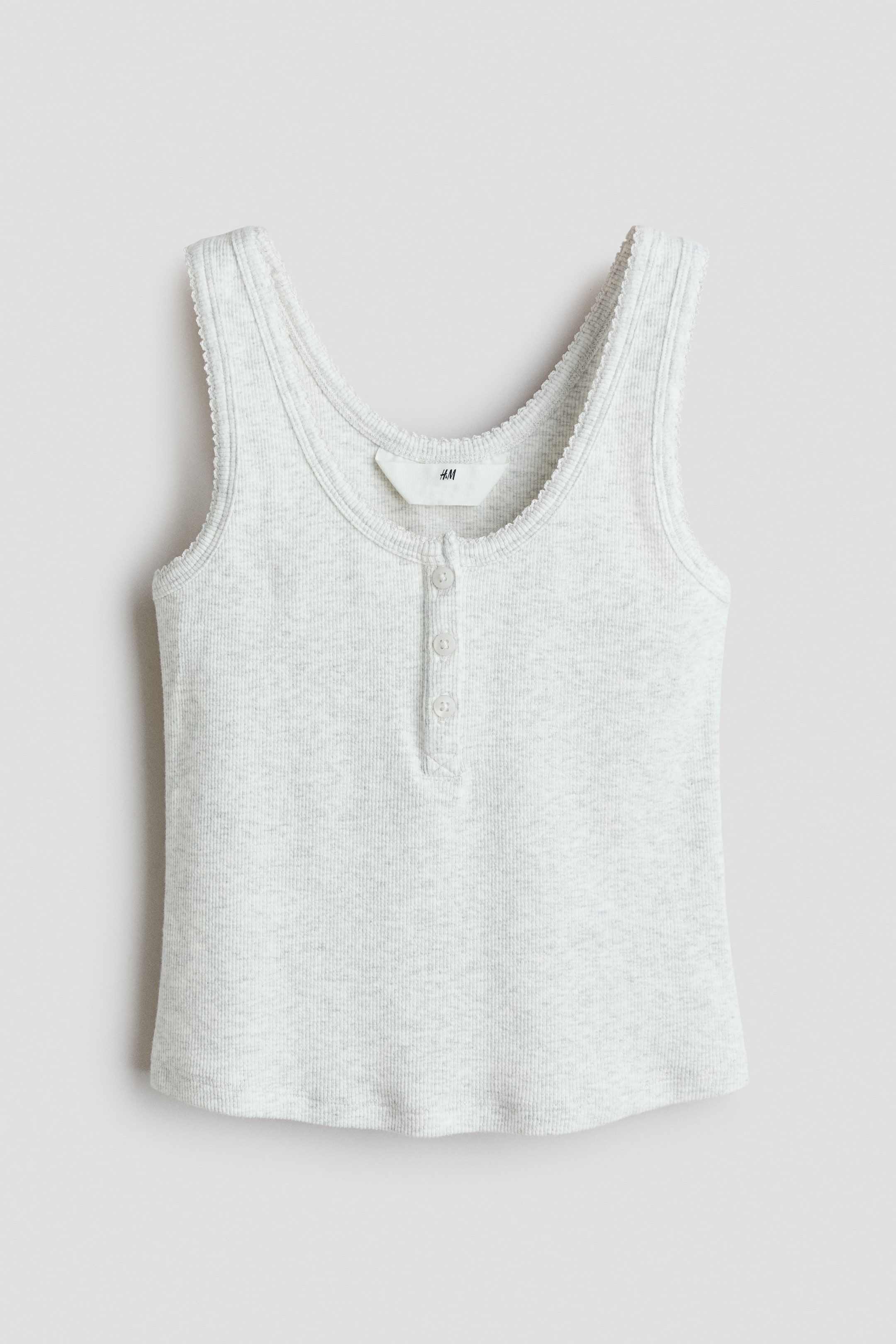 View larger image: A light grey ribbed tank top is shown from the front, featuring a scoop neckline with delicate picot trim and a partial button placket with three buttons. The sleeveless top has a straight hemline and a soft, textured knit structure.