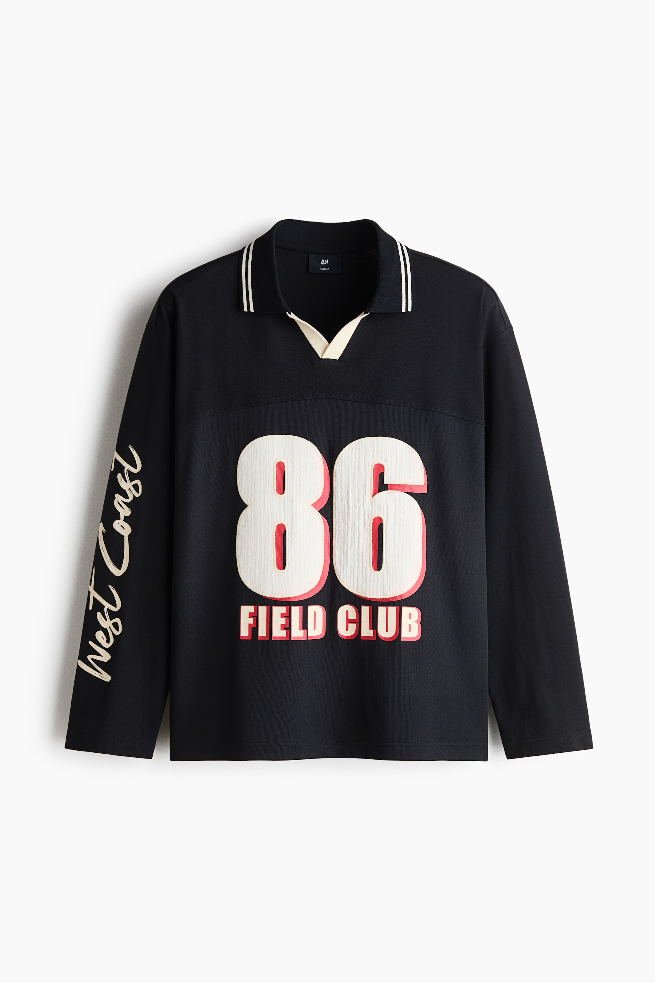 View larger image: A black long-sleeved polo shirt is shown from the front, featuring an open collar with white contrasting trim and stripes, dropped shoulders, and a straight-cut hem. The front displays a large white and red "86" graphic with "FIELD CLUB" printed below, while the right sleeve features the words "West Coast" in cream-coloured script.