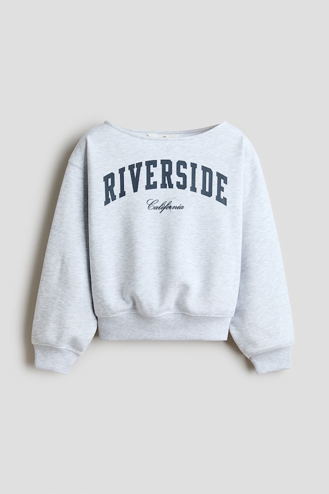 A light grey mÃ©lange sweatshirt is shown from the front, featuring a wide boat neckline, dropped shoulders, and ribbed trim at the cuffs and hem. The chest features the word "RIVERSIDE" in arched navy block lettering with "California" printed in cursive script below it. - 1
