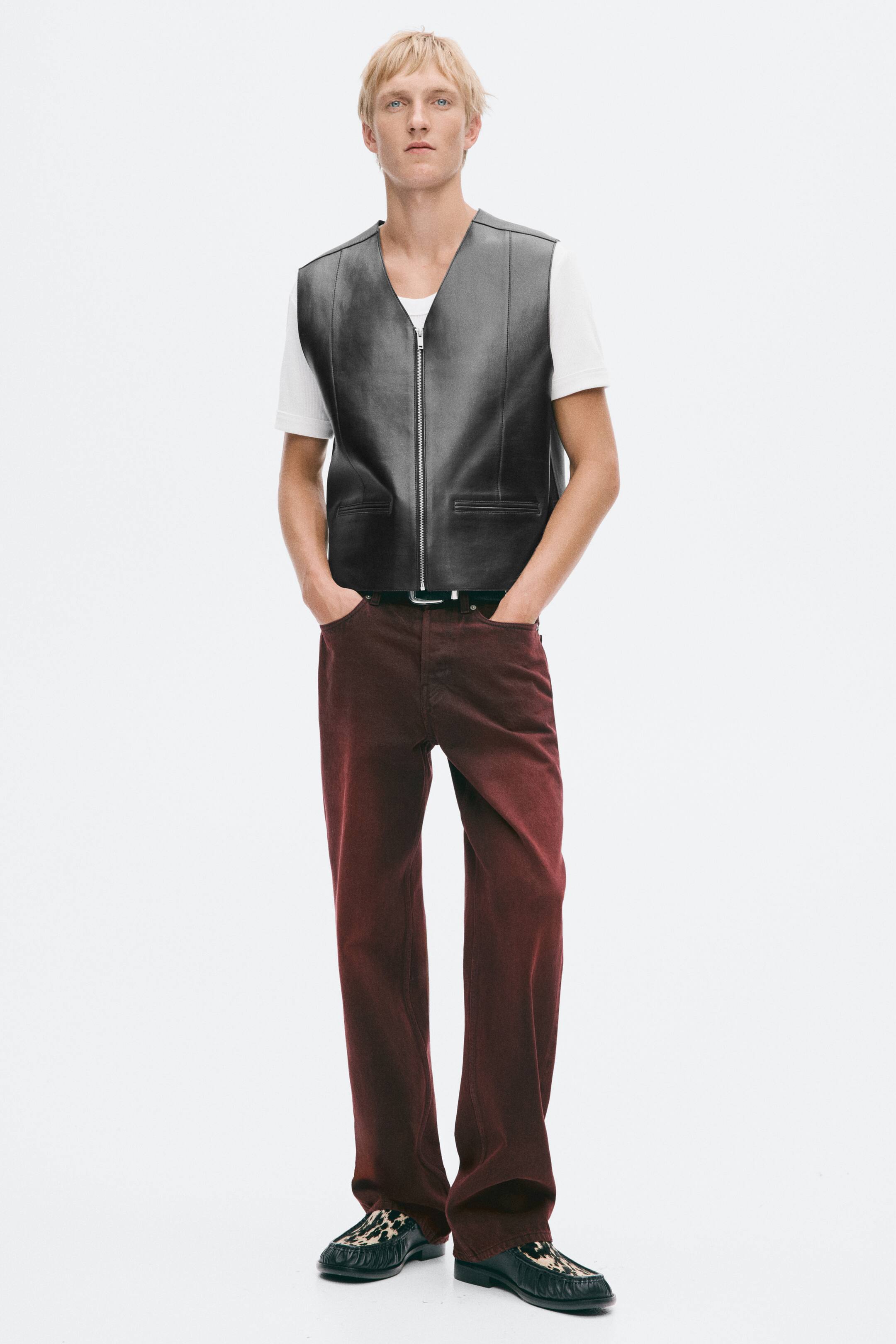 View larger image: A dark leather vest is being worn by the model over a white T-shirt. It features a front zip closure, jetted front pockets, visible front seams, and a yoke.