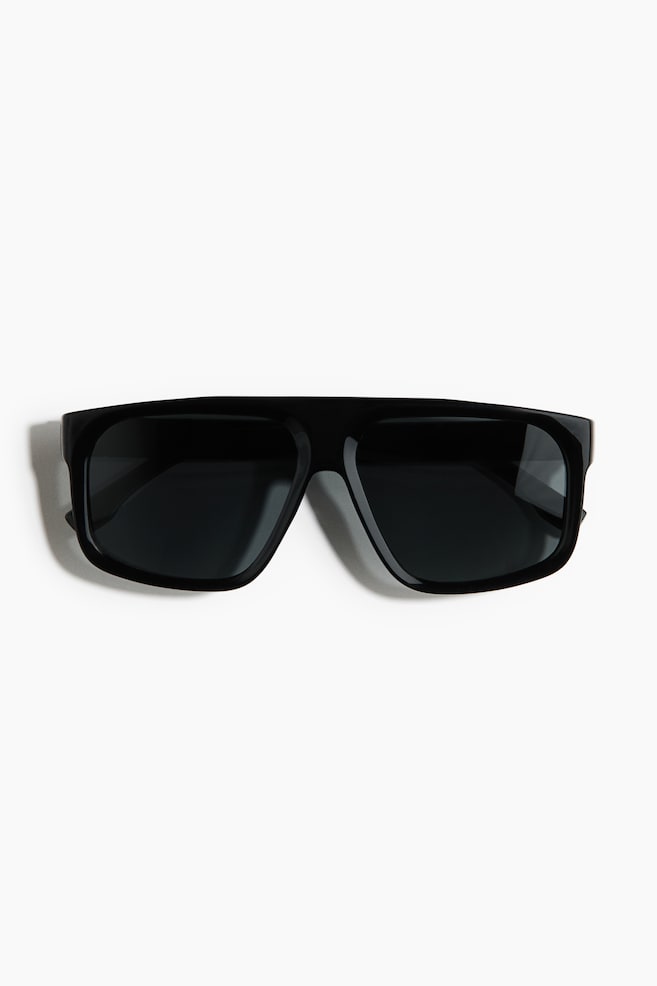 Black sunglasses featuring a wide, flat-top rectangular frame with dark lenses, presenting a slight forward angle. - 1