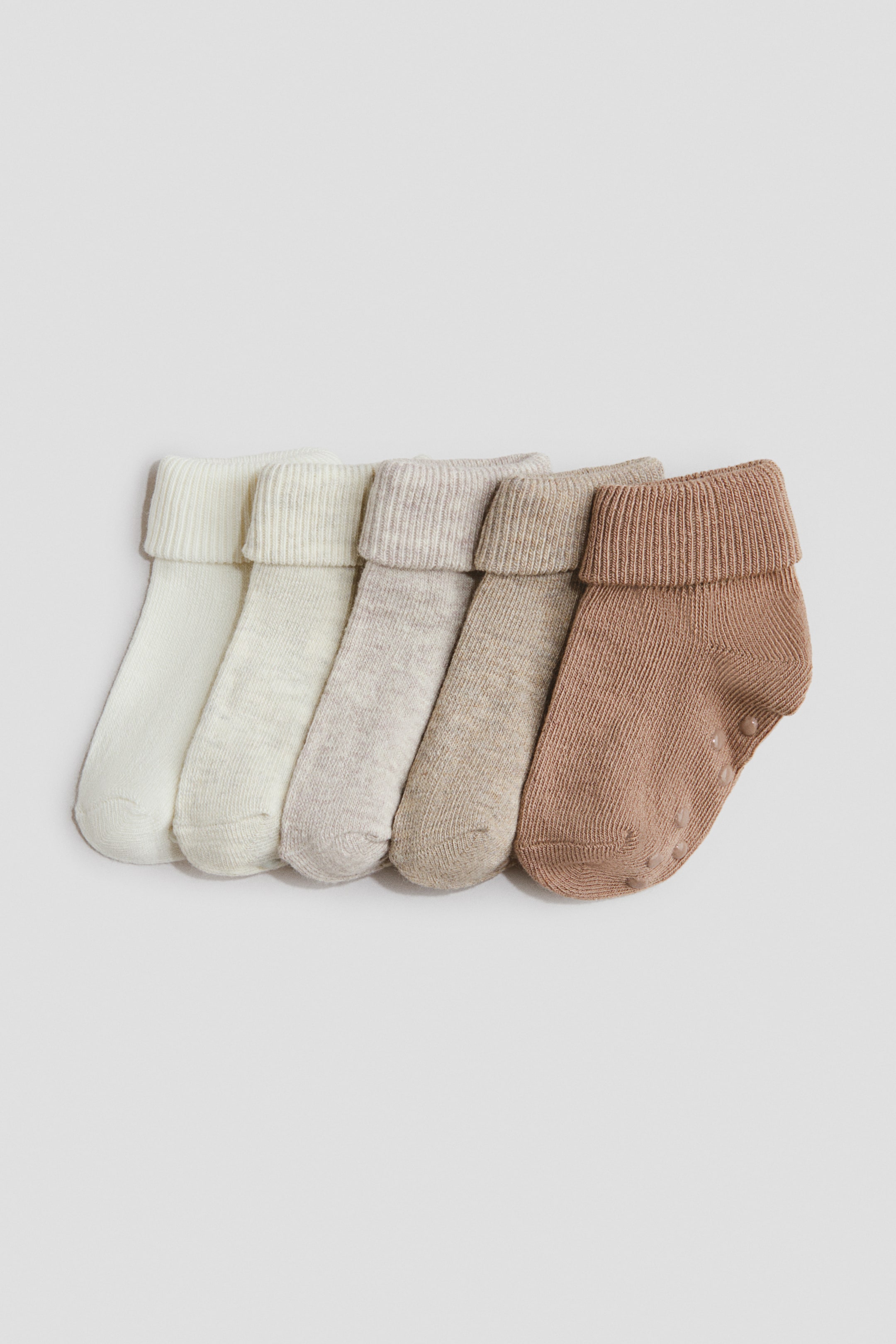 Größeres Bild ansehen: Fünf Socken werden präsentiert, die in der Farbe von Cremeweiß zu Hellbraun übergehen. Jede Socke zeichnet sich durch eine weiche, fein gestrickte Textur, einen umgeschlagenen Schaft und rutschfeste Protektoren an der Sohle der rechten Socke aus.