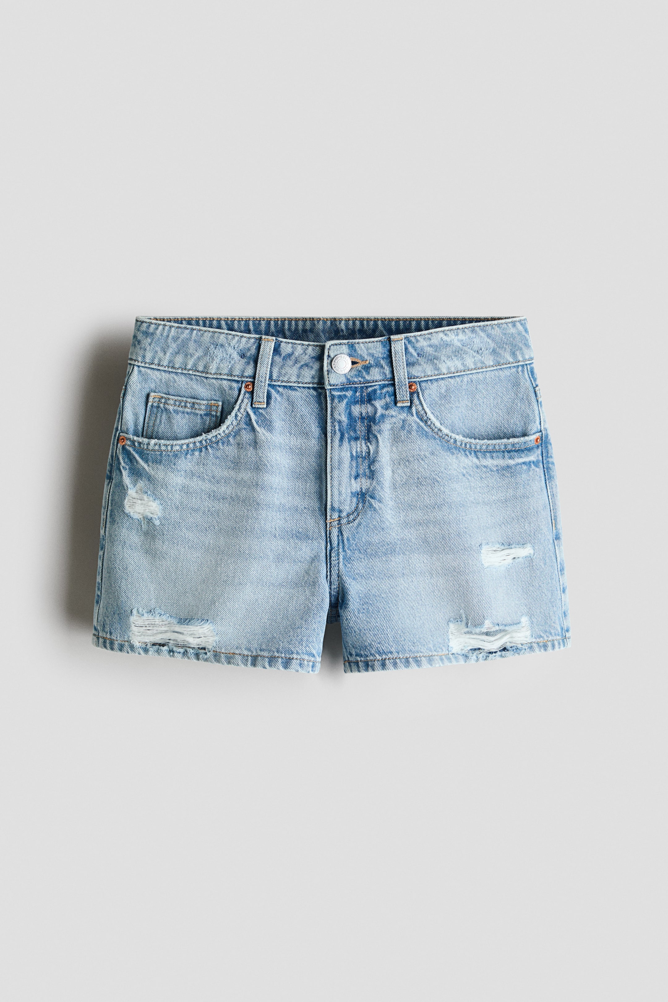 View larger image: Five-pocket cotton denim shorts are displayed from the front, showcasing a light blue wash with distressed details. The shorts boast a relaxed fit, an adjustable elastic waistband, a zip fly with a button closure, and raw-edge hems.