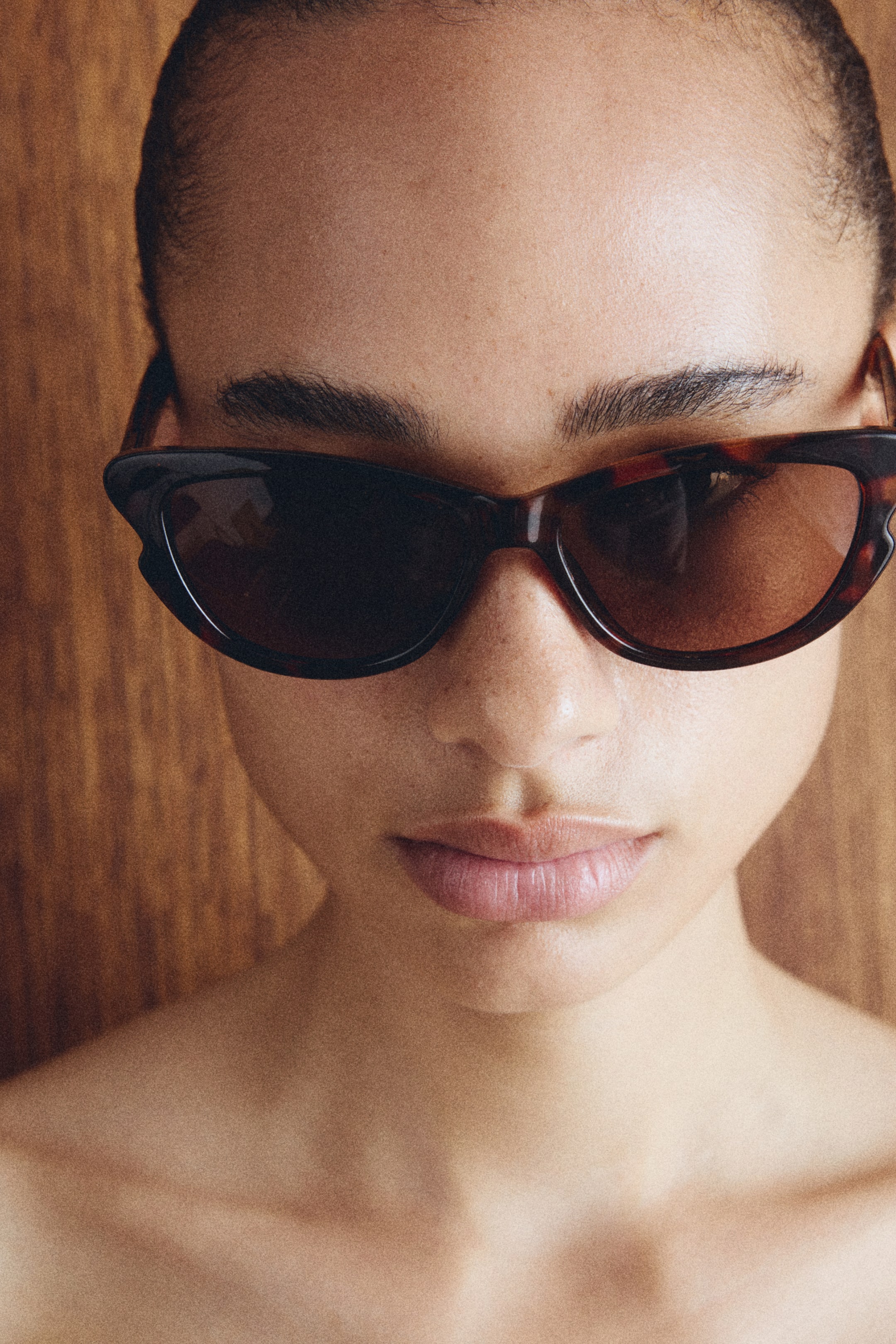 View larger image: Tortoiseshell sunglasses are being worn, showcasing dark brown frames with a cat-eye shape and subtly upswept outer edges. The lenses are a rich, dark brown tint.