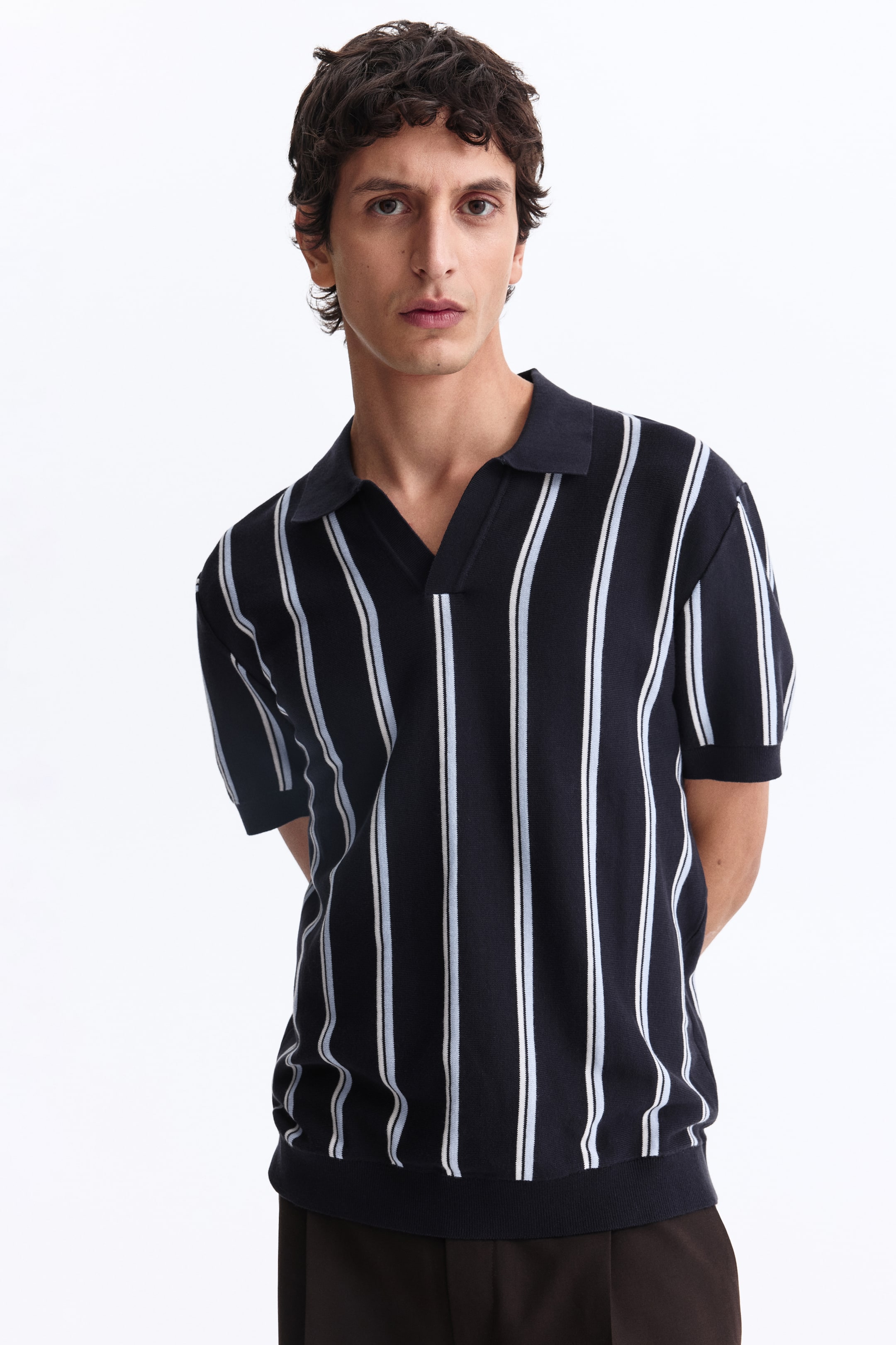 View larger image: A navy knit polo shirt features white and light-blue vertical stripes. It is designed with a polo collar, a V-neck opening, short sleeves, and ribbed hem and cuffs.