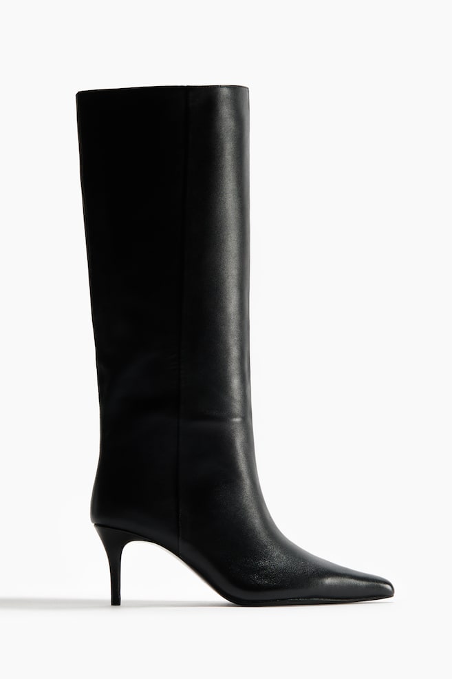A black boot showcasing a tall, sleek leather shaft, pointed toe, and a slim kitten heel, depicted in a side profile. - 1