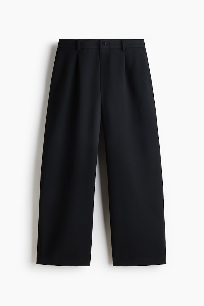 Eine schwarze Hose mit weitem Bein ist von vorne zu sehen und verfÃ¼gt Ã¼ber einen strukturierten Bund mit GÃ¼rtelschlaufen, einen mittigen Knopfverschluss und vordere Bundfalten, die in einen lÃ¤ssigen, geraden Fall Ã¼bergehen. - 1