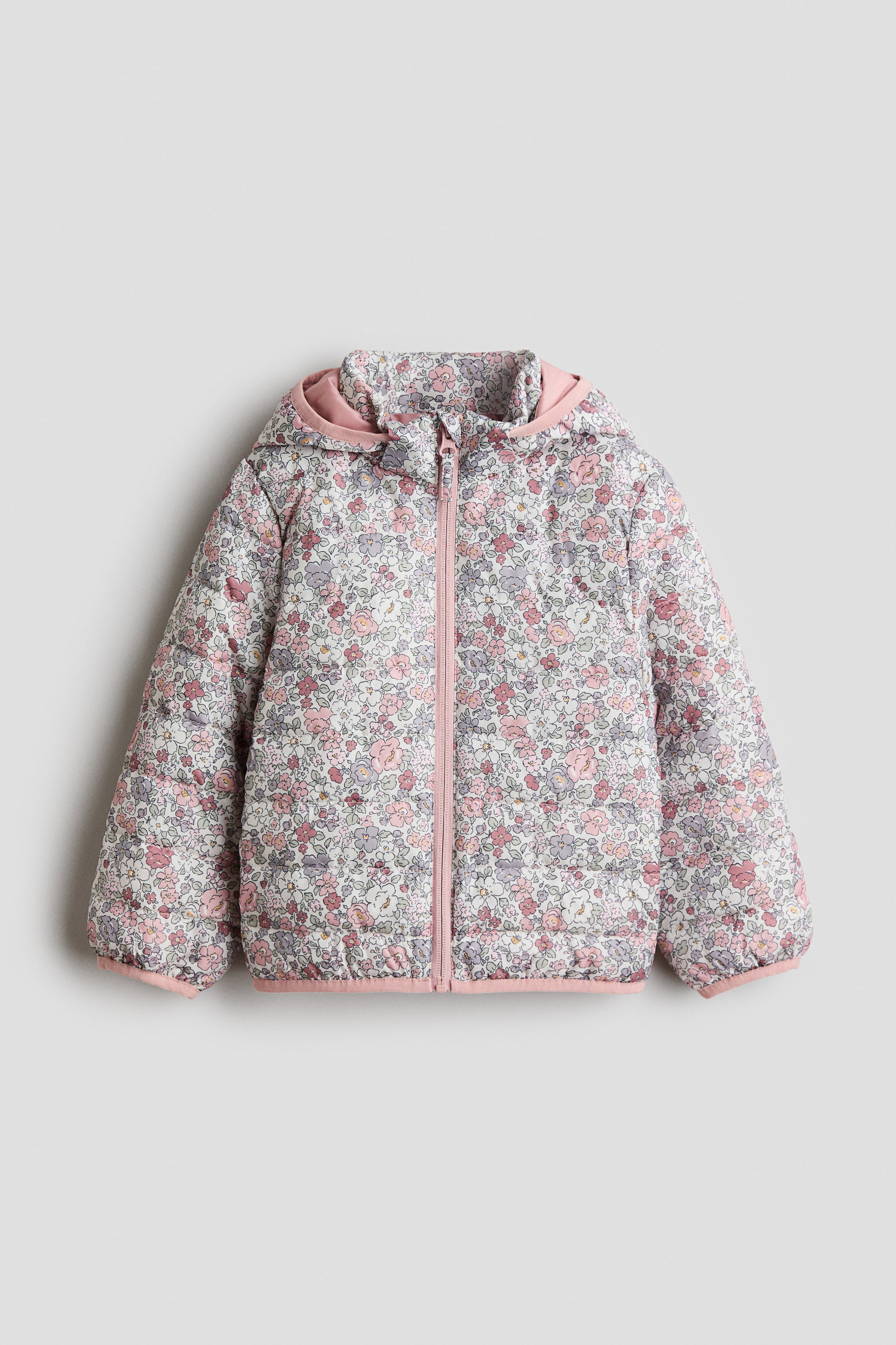 Größeres Bild anzeigen: Eine von vorne gezeigte, wattierte Jacke mit einem gesteppten Blumenmuster in Rosa, Violett und Weiß, mit einer Kapuze mit einfarbig rosa Futter und rosa Jersey-Einfassung, einem Stehkragen, einem rosa Frontreißverschluss mit Kinnschutz sowie rosa Jersey-Einfassungen an den Ärmelabschlüssen und am Saum.