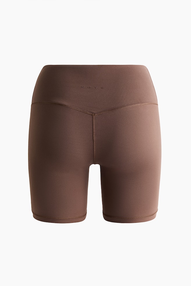 Sports cycling shorts with SoftMove are displayed facing front in a brown color, featuring a high-waisted design. A V-shaped seam is visible below the wide waistband, which is subtly embossed with the word "MOVE" at the center, and flatlock seams are running down the legs to the mid-thigh length. - 1