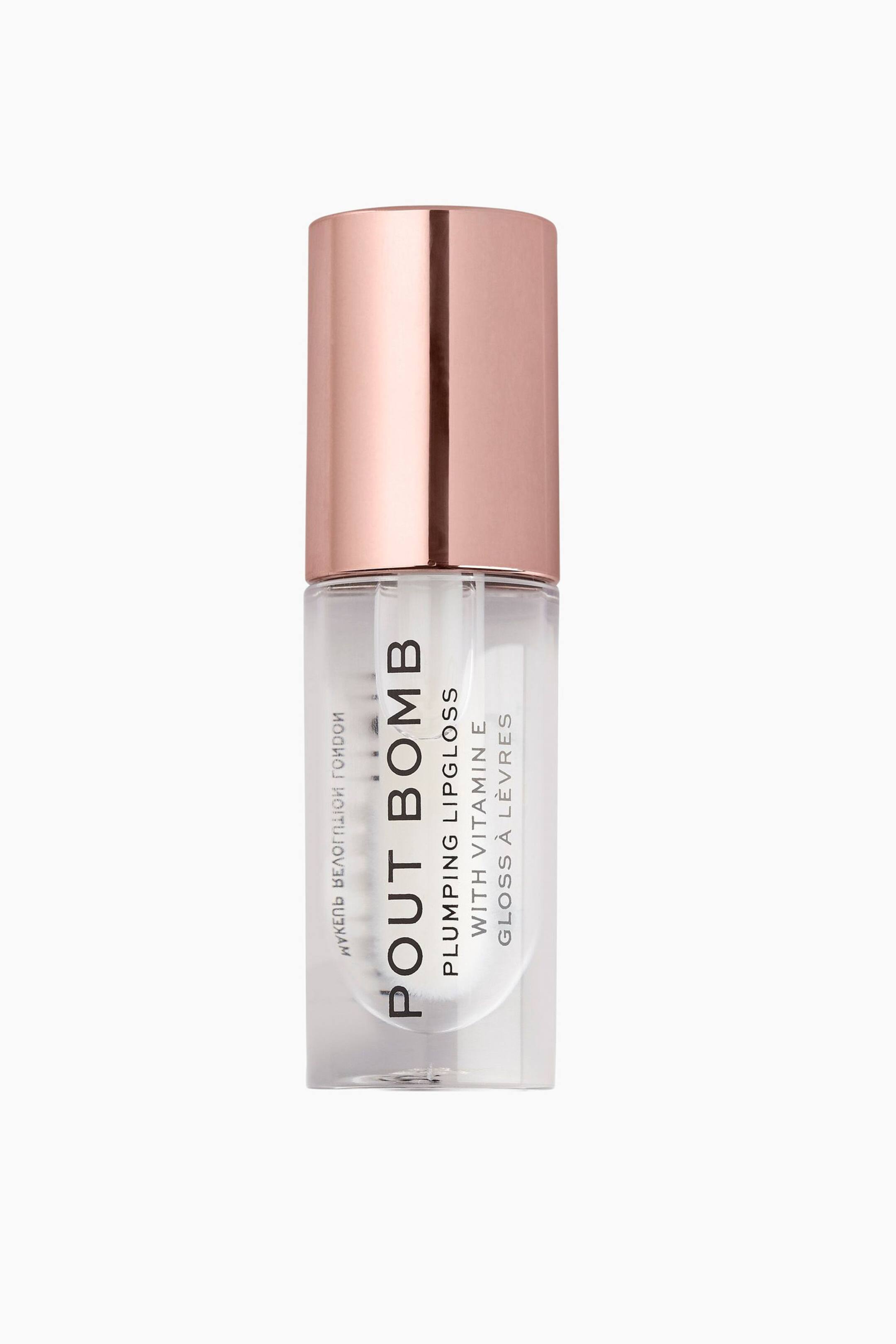Visa större bild: En cylindrisk tub med genomskinligt läppglans står upprätt och har ett metalliskt roséguldfärgat lock. Den transparenta behållaren visar vertikal svart text som lyder "POUT BOMB PLUMPING LIPGLOSS WITH VITAMIN E."