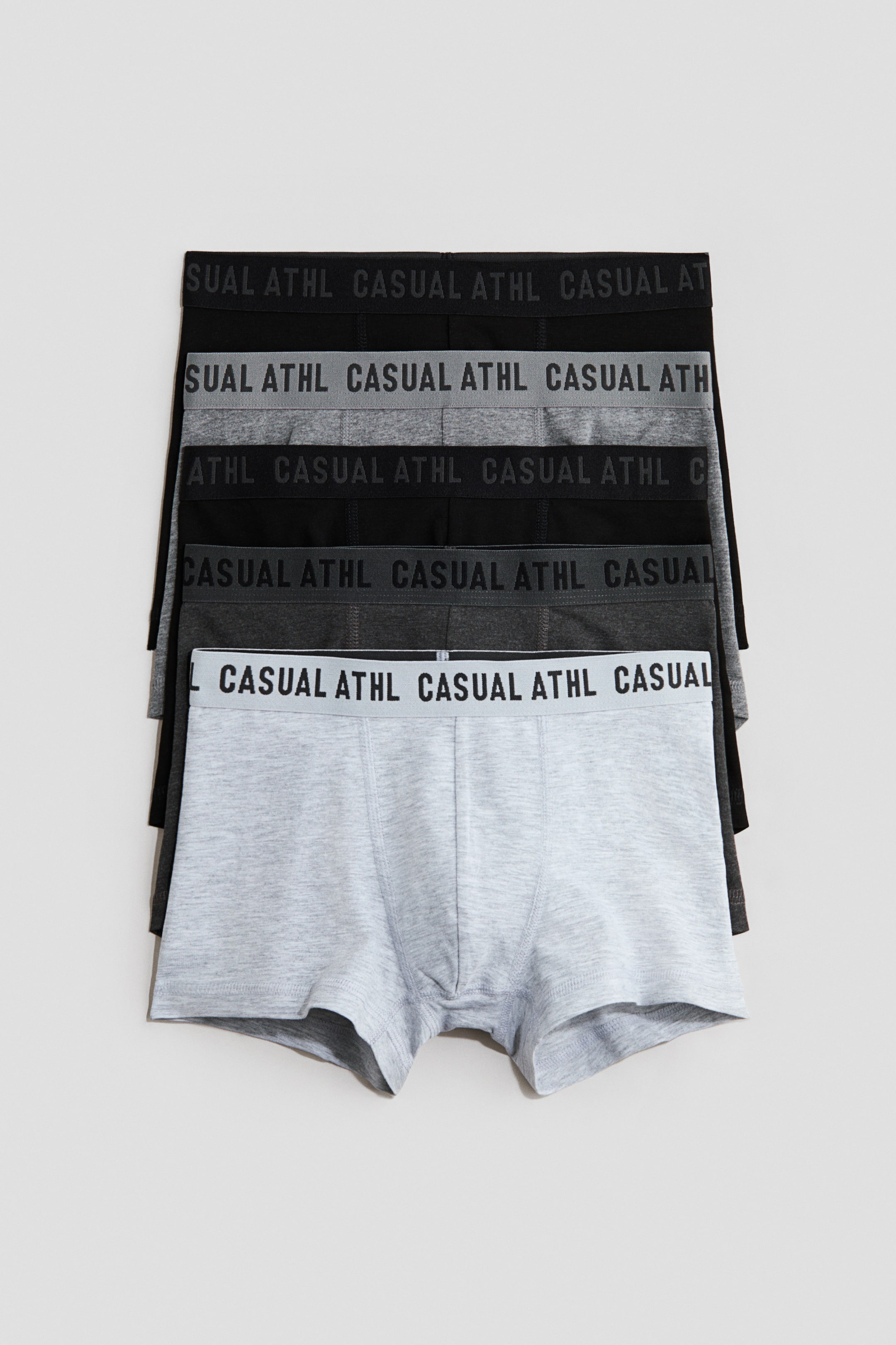 Ver imagem maior: Calções em jersey de algodão com pernas curtas, cintura elástica e frente forrada estão empilhados, apresentando a sua parte frontal. Cada par possui uma cintura elástica com o texto "CASUAL ATHL" e aparece em tons de cinza e preto.