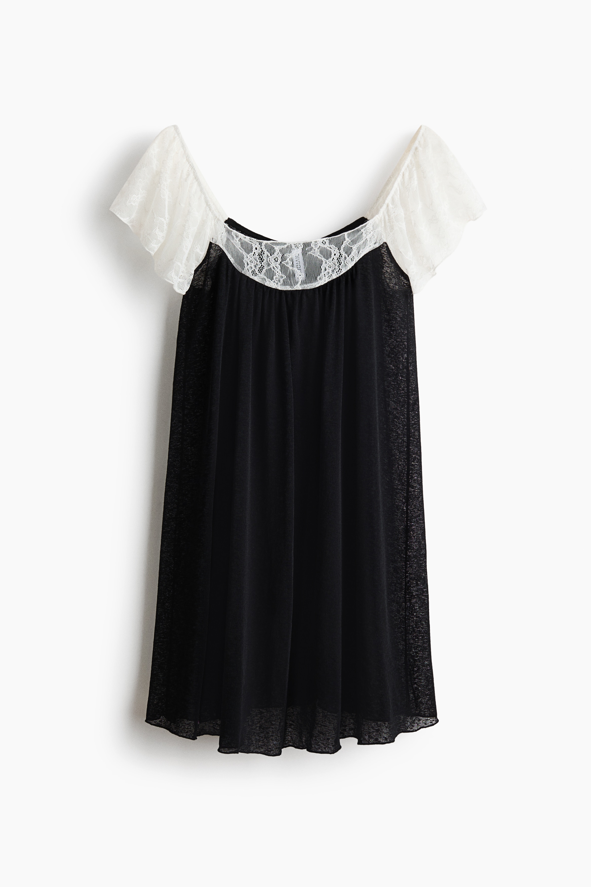 A loose-fit black mini dress is being worn by the model sitting on the floor. The dress features a gathered scoop neckline with a contrasting white lace inset and matching lace flutter sleeves.