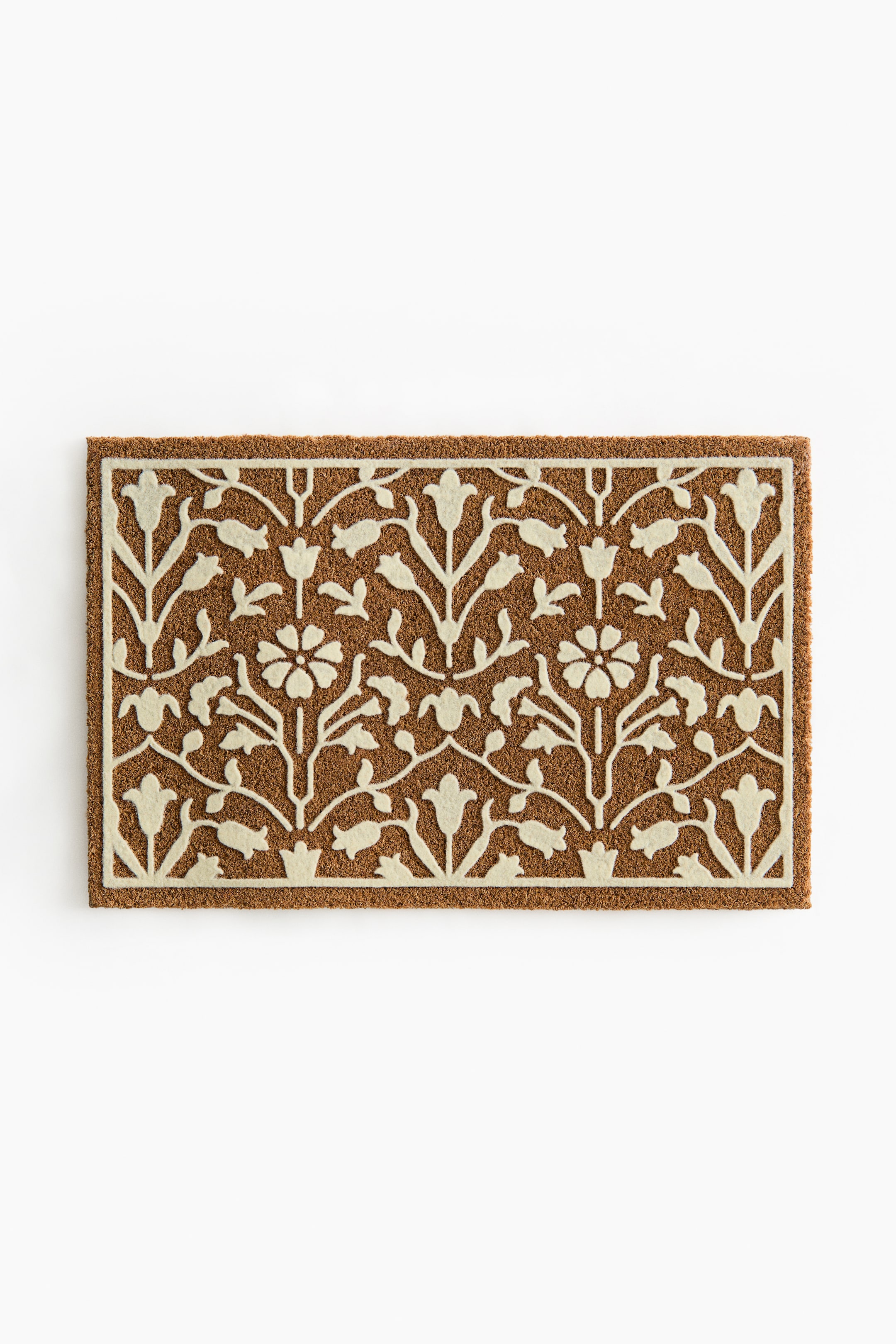 View larger image: The rectangular coir mat showcases an intricate off-white floral and foliage pattern set against a brown textured background, complete with a matching solid border. This description provides a front-view perspective of the mat.
