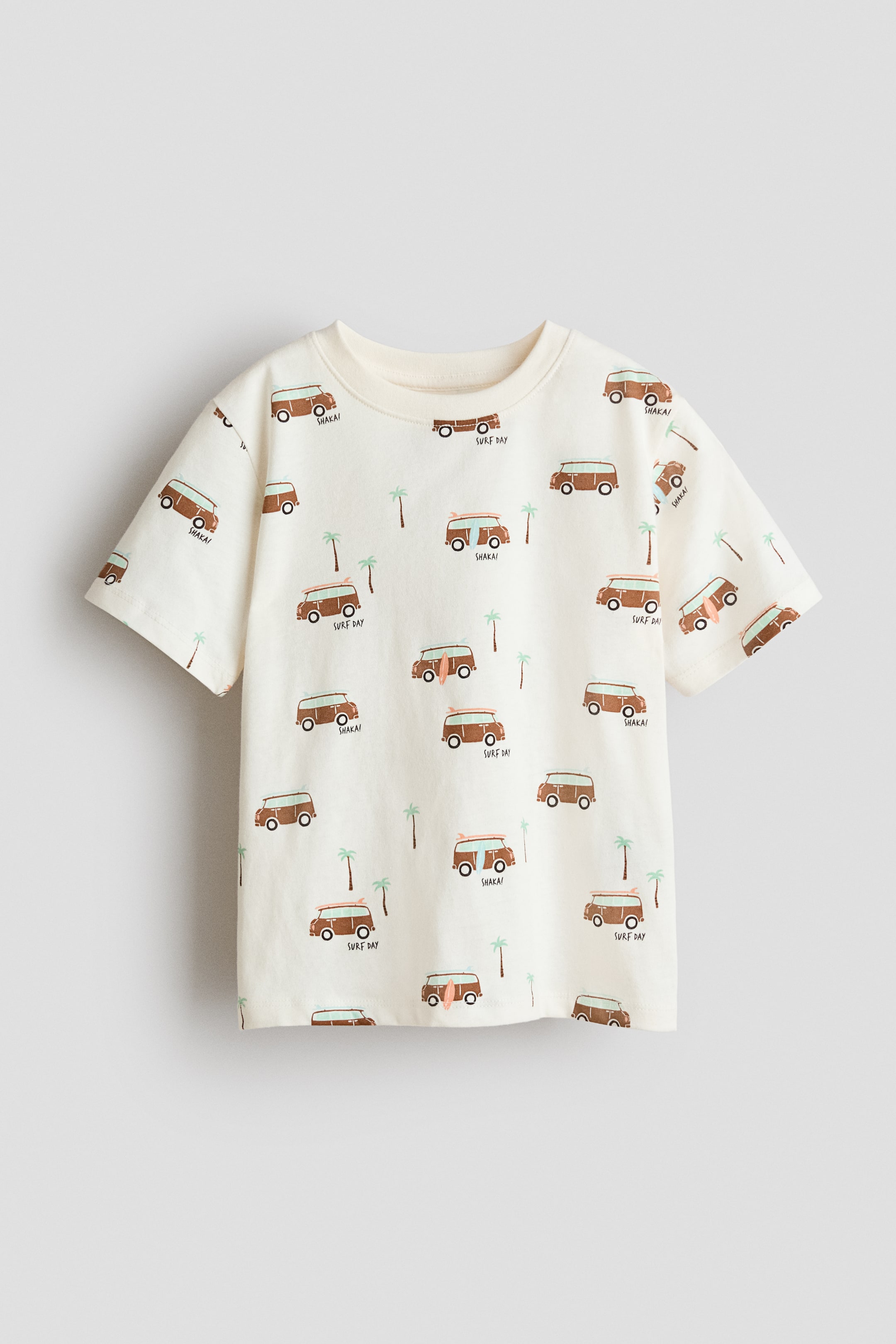 View larger image: This T-shirt showcases its front view, adorned with an all-over print of brown camper vans and green palm trees on a cream jersey knit fabric. It is crafted with a ribbed round neckline, dropped shoulders, and a straight-cut hem.