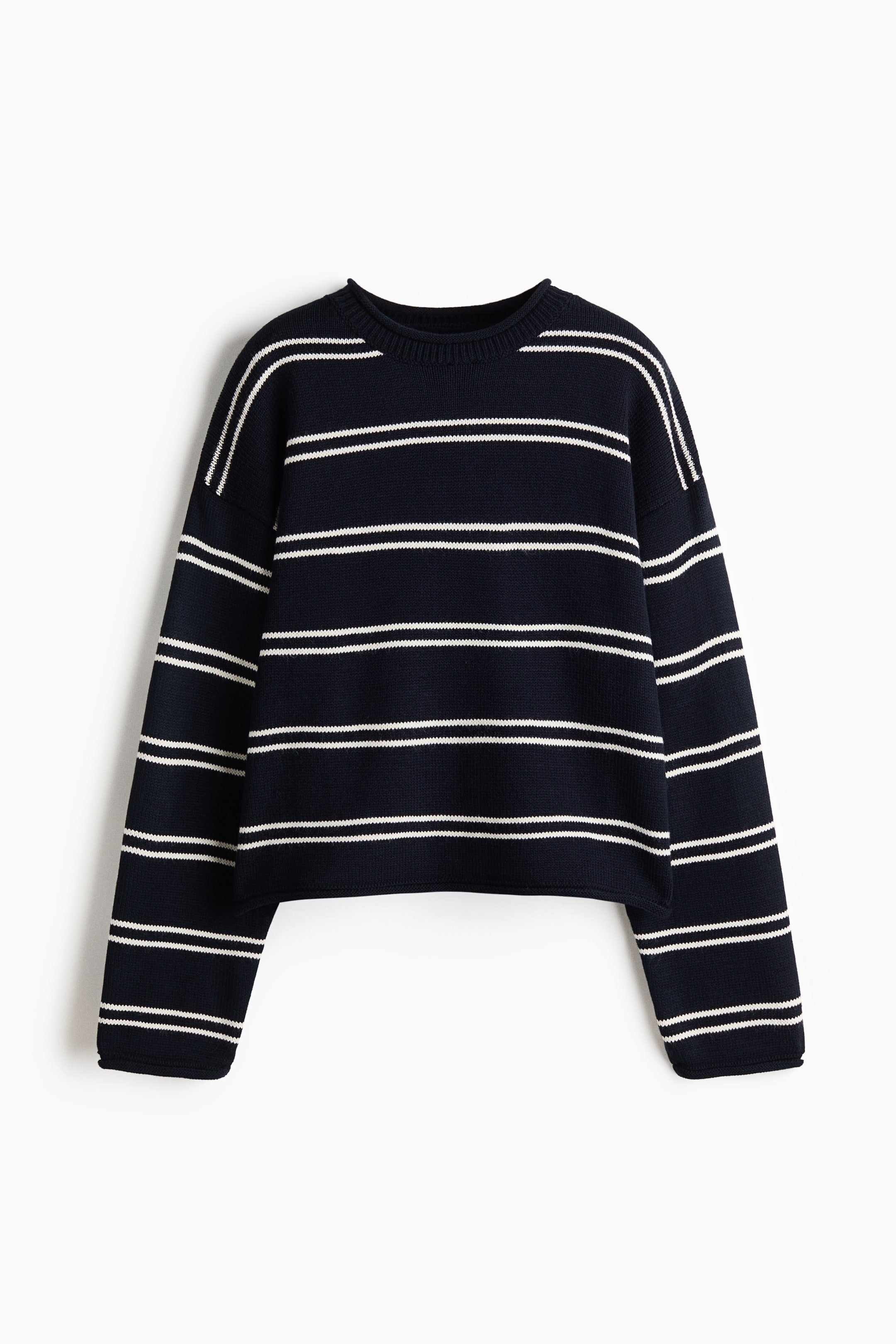 Größeres Bild ansehen: Ein kurzer, oversized gestrickter Pullover in Marineblau mit weißen horizontalen Streifen ist frontal dargestellt. Das Kleidungsstück zeigt einen gerippten Rundhalsausschnitt, überschnittene Schultern und lange Ärmel, wobei die Bündchen und der Saum mit gerollten Kanten abschließen.