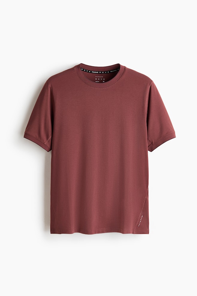 A regular fit sports t-shirt in dark red is facing front, featuring a subtle textured fabric, a round neck, and short sleeves with simple hems. Subtle diagonal seams are detailing the sides of the t-shirt, and "DRYMOVE" is printed vertically near the bottom right hem. - 1