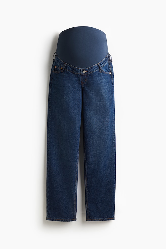 Front-facing maternity jeans are showcasing a dark blue cotton denim with a 5-pocket style. A wide, dark blue jersey panel is extending upwards from the waistband, where elastication is visible at the sides. The jeans are designed with a fake fly and a single visible button, and are cut with straight legs. - 1