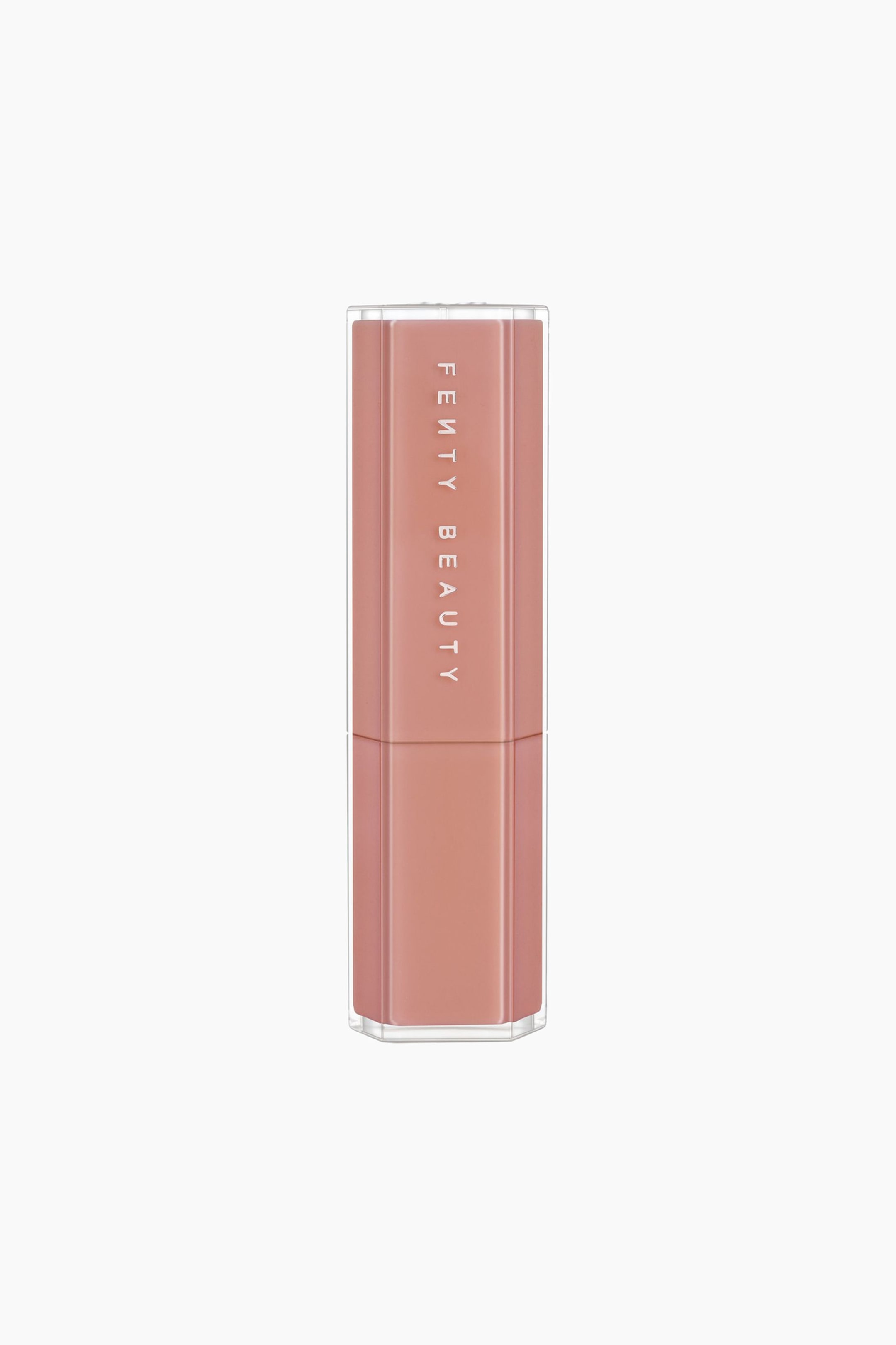 Näytä suurempi kuva: Gloss Bomb Stix High-shine Gloss Stick on pystyssä, ja siinä on kahdeksankulmainen läpinäkyvä ulkokuori, jonka läpi näkyy pölyisen ruusun sävyinen sisäosa. Brändin nimi "FENTY BEAUTY" on painettu pystysuunnassa valkoisilla kirjaimilla korkin etupuolelle.