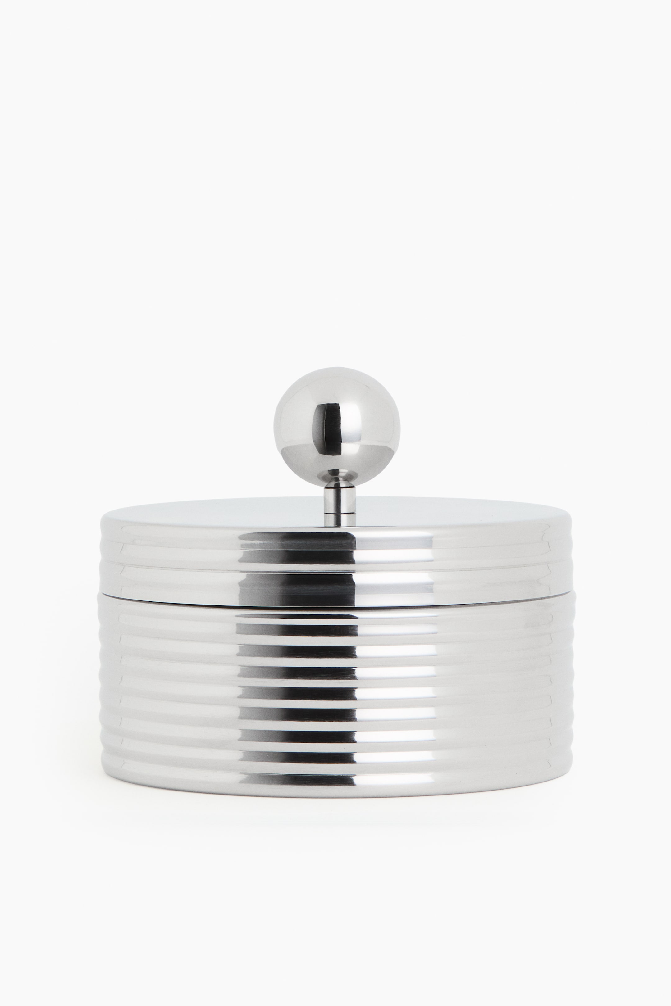 View larger image: A front-facing, silver-toned cylindrical container showcases horizontal ridged detailing around its body. It is crowned with a flat lid, featuring a spherical knob handle at its center.