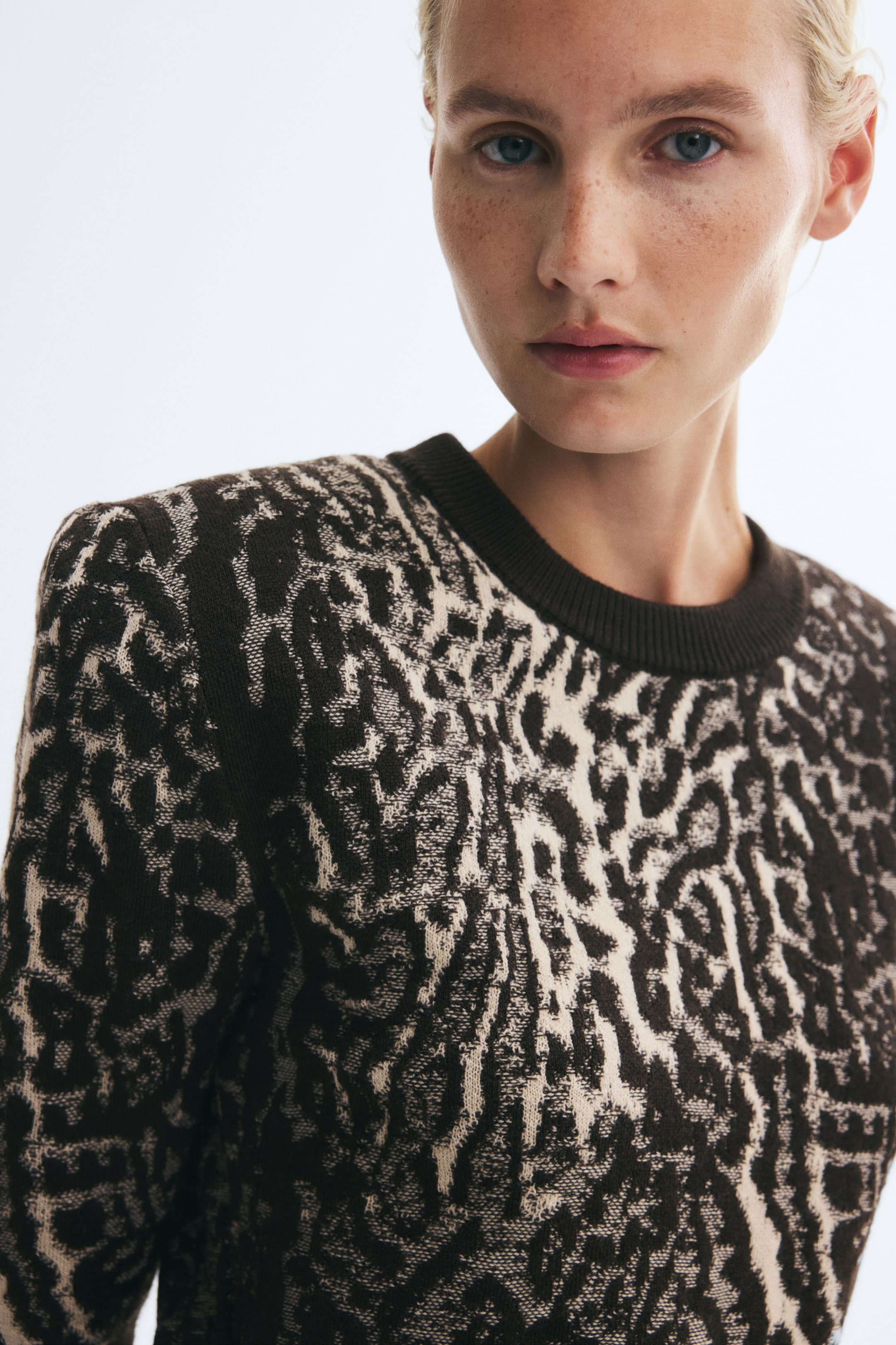 View larger image: A jacquard-knit jumper with an abstract dark brown and cream pattern, a round rib-trimmed neckline and structured shoulder pads is being worn by the model.