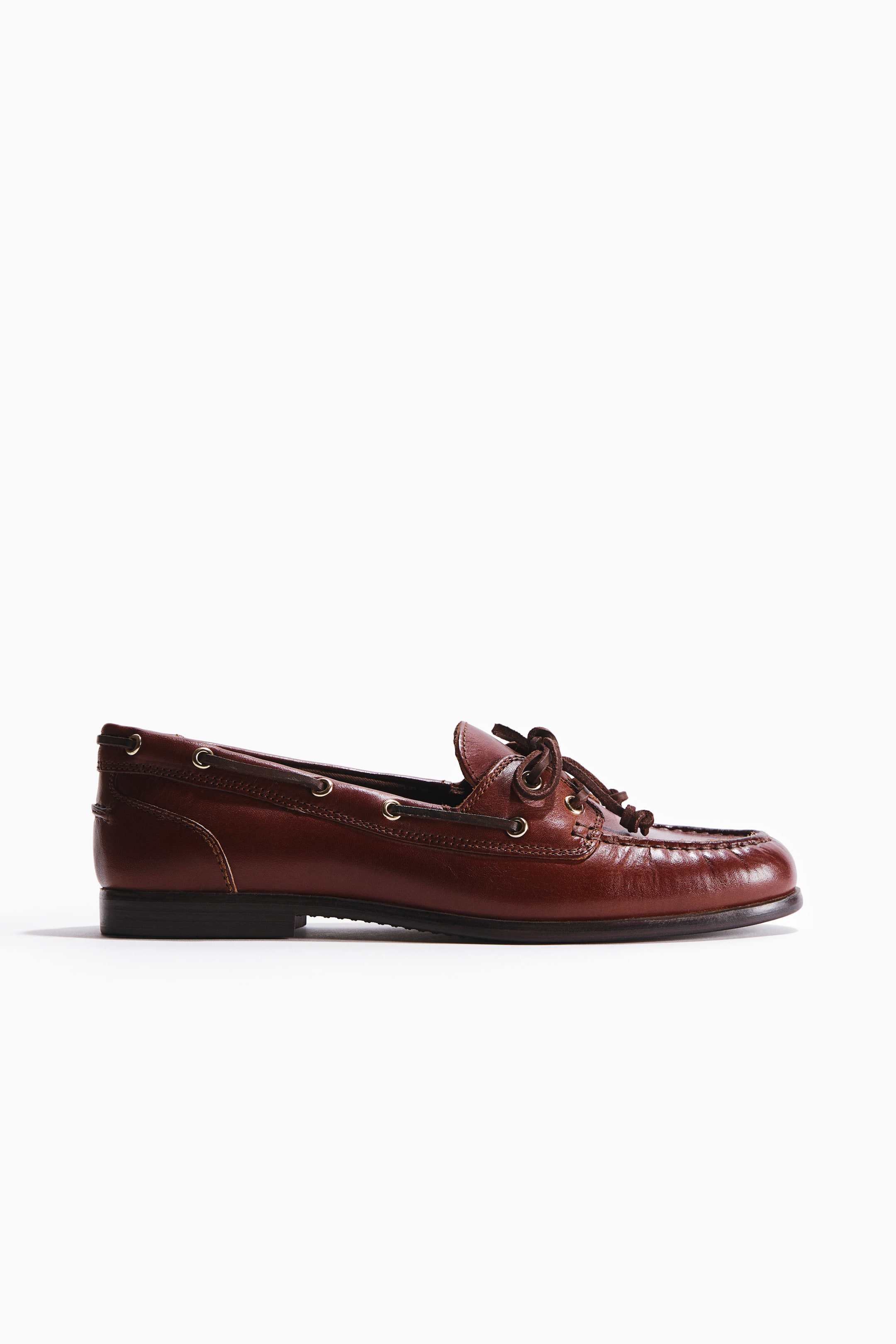 Agrandir l'image: Une chaussure de pont en cuir marron est présentée en profil latéral, avec un laçage passant par des œillets le long des côtés et noué à l'avant, rehaussée par une couture mocassin autour de l'orteil.