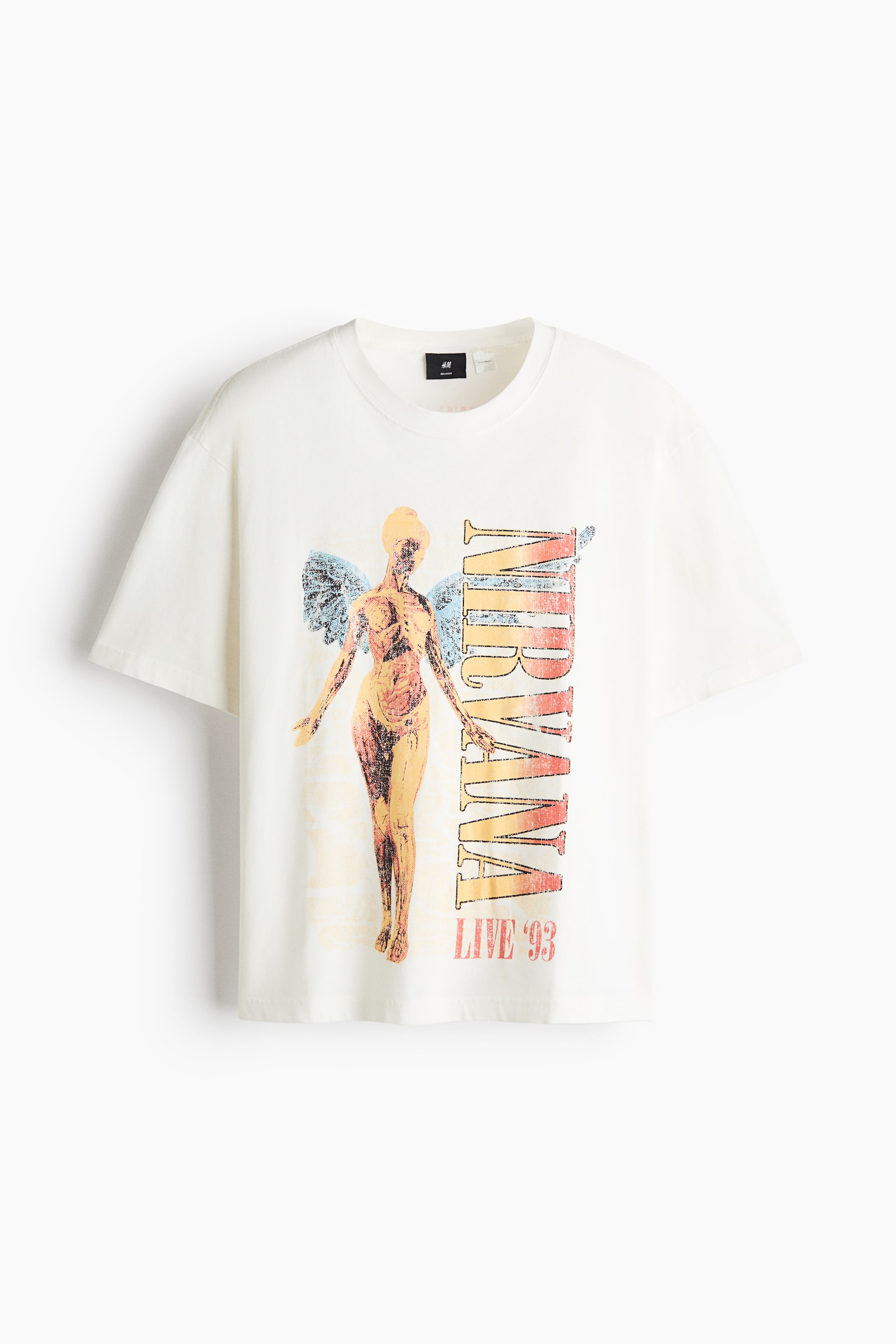 View larger image: An off-white, relaxed-fit cotton t-shirt is shown from the front, featuring dropped shoulders, a ribbed crew neckline, and a straight hem. The front displays a printed graphic of an anatomical angel with light blue wings beside vertical "NIRVANA" lettering and "LIVE '93" in a distressed warm-toned gradient.