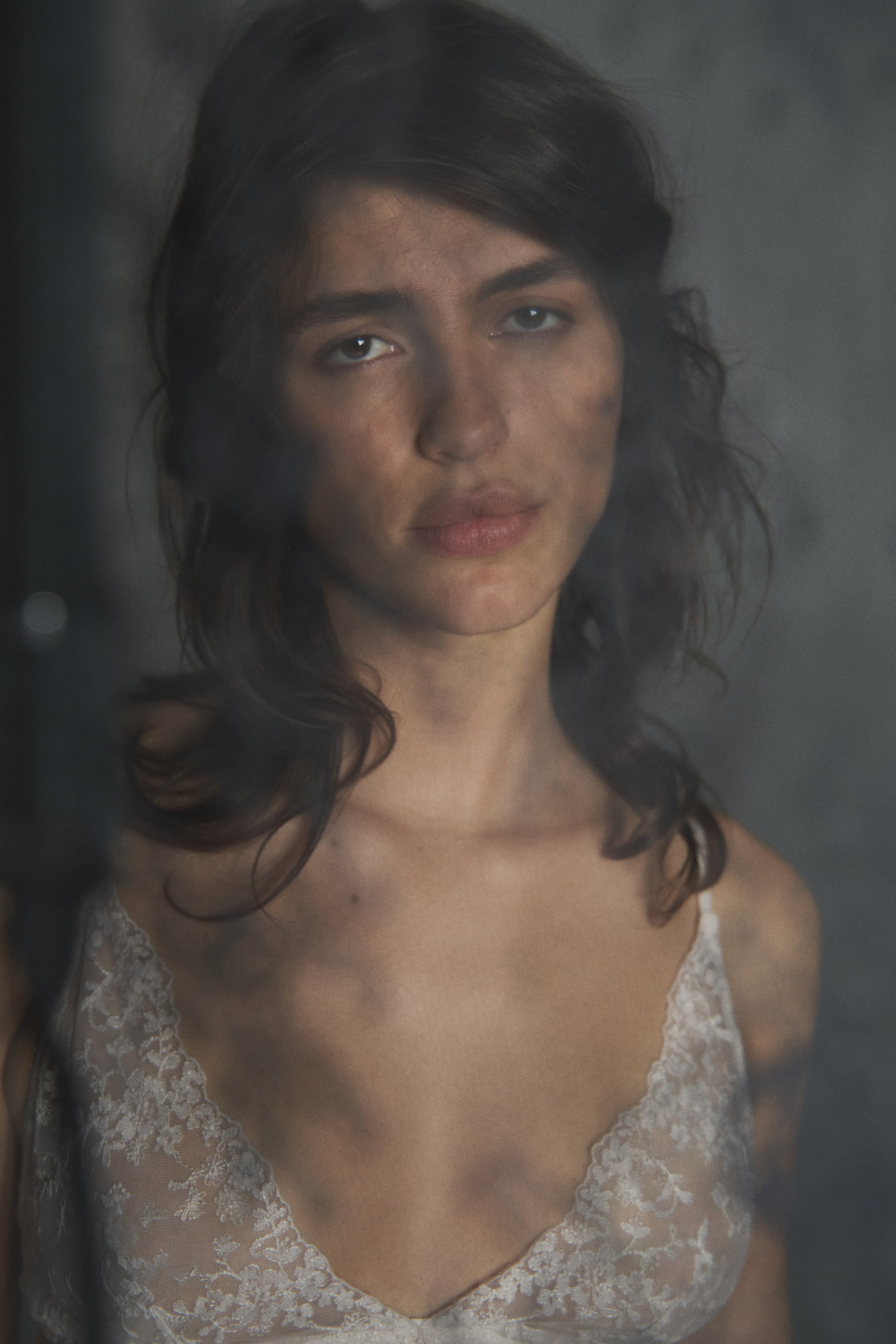 View larger image: A light-colored sheer lace camisole features a V-neckline, thin spaghetti straps, and an intricate floral lace pattern across the bust.