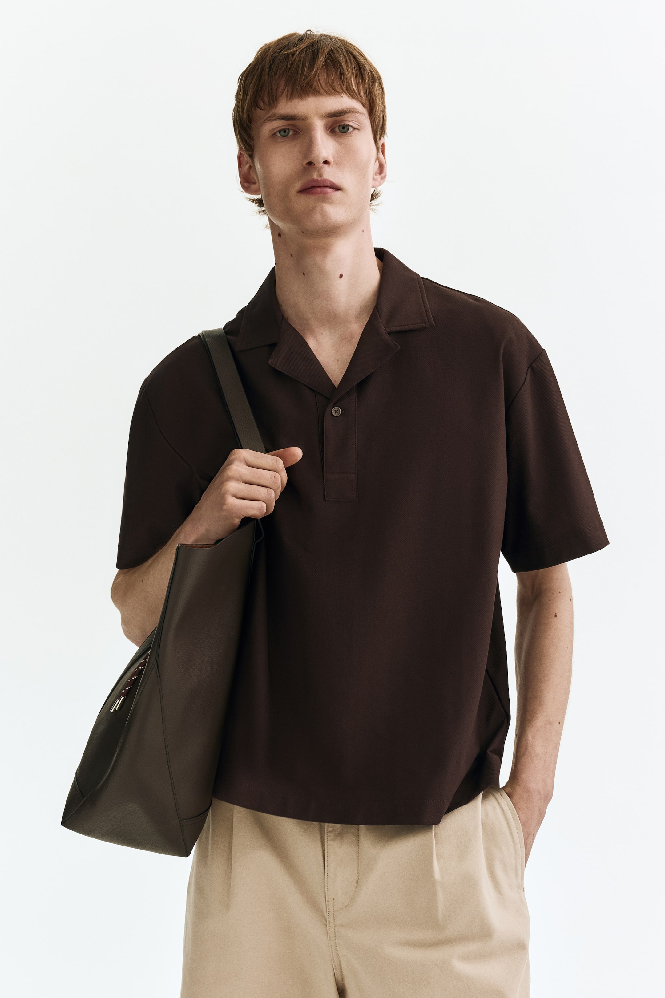 View larger image: A dark brown short-sleeve shirt featuring an open camp collar and a short two-button placket. It offers a relaxed fit with a straight hem, facing forward.