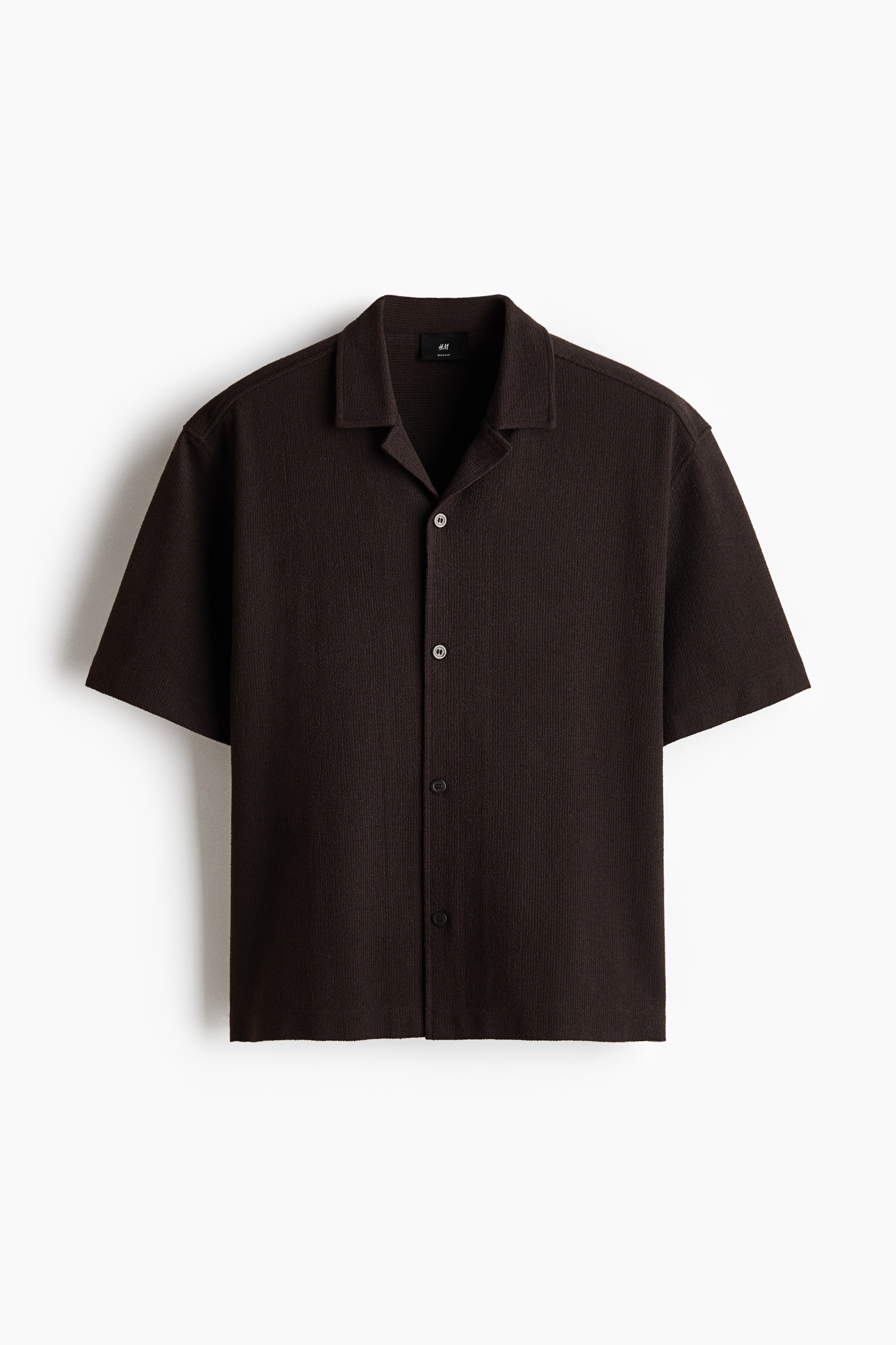 Xem ảnh lớn hơn: Áo sơ mi tay ngắn màu nâu đậm bằng vải jacquard jersey đang được hiển thị từ phía trước. Sản phẩm có cổ áo kiểu resort, hàng nút giấu, và đường viền cắt thẳng, mang lại dáng vẻ thoải mái.