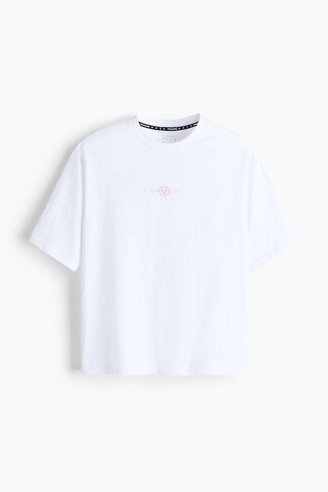 A white boxy-style sports T-shirt is presenting its front view, featuring a crew neck with a black interior neck tape displaying white 'TRAINING MOVE' text and a white label showing 'DRYMOVE'. A small red and white 'DEAD D.E.R. UNNERS' graphic is centered on the chest. - 1