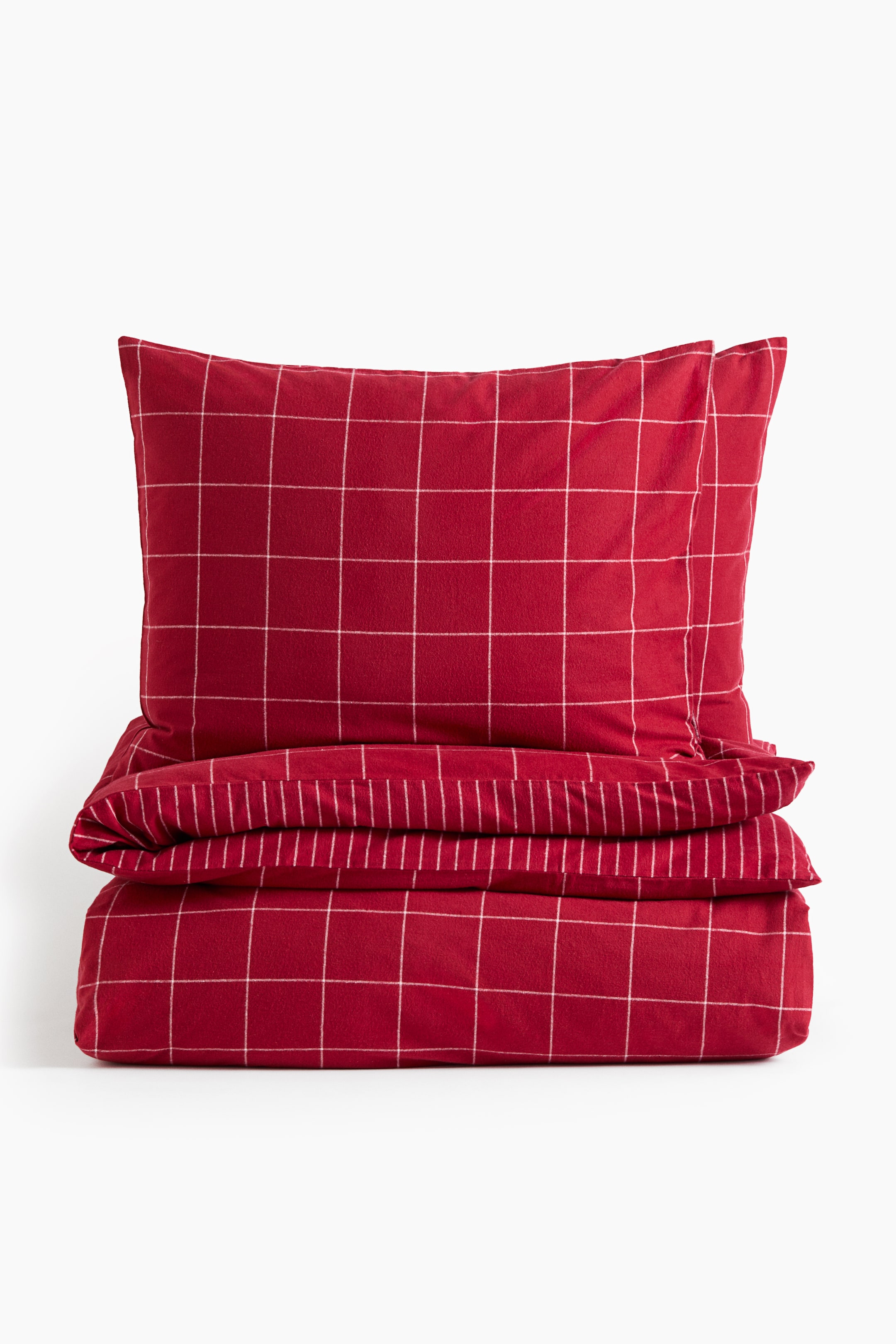 View larger image: A red cotton flannel quilt cover set is shown front-facing, featuring a white windowpane check pattern. The neatly folded quilt cover is placed at the bottom, displaying a white pinstripe pattern on its reverse fold, while two matching pillowcases stand upright directly behind it.