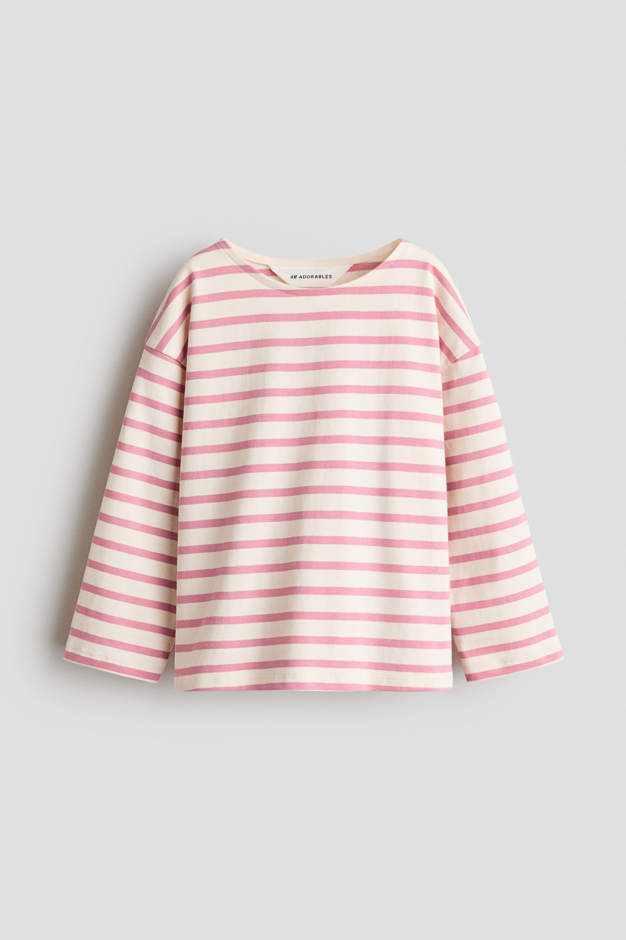 查看大圖: H&M Adorables 的針織上衣平放展示,奶油色背景上有水平的粉紅色條紋。它具有寬圓領口、低垂肩線和長而寬的袖子。