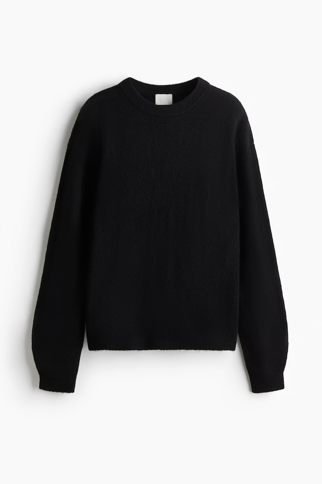 Un pull noir se présente comme FRONT, avec une texture en maille douce, un col rond bordé de côtes, des épaules tombantes, des manches longues, et des poignets et un ourlet côtelés. - 1