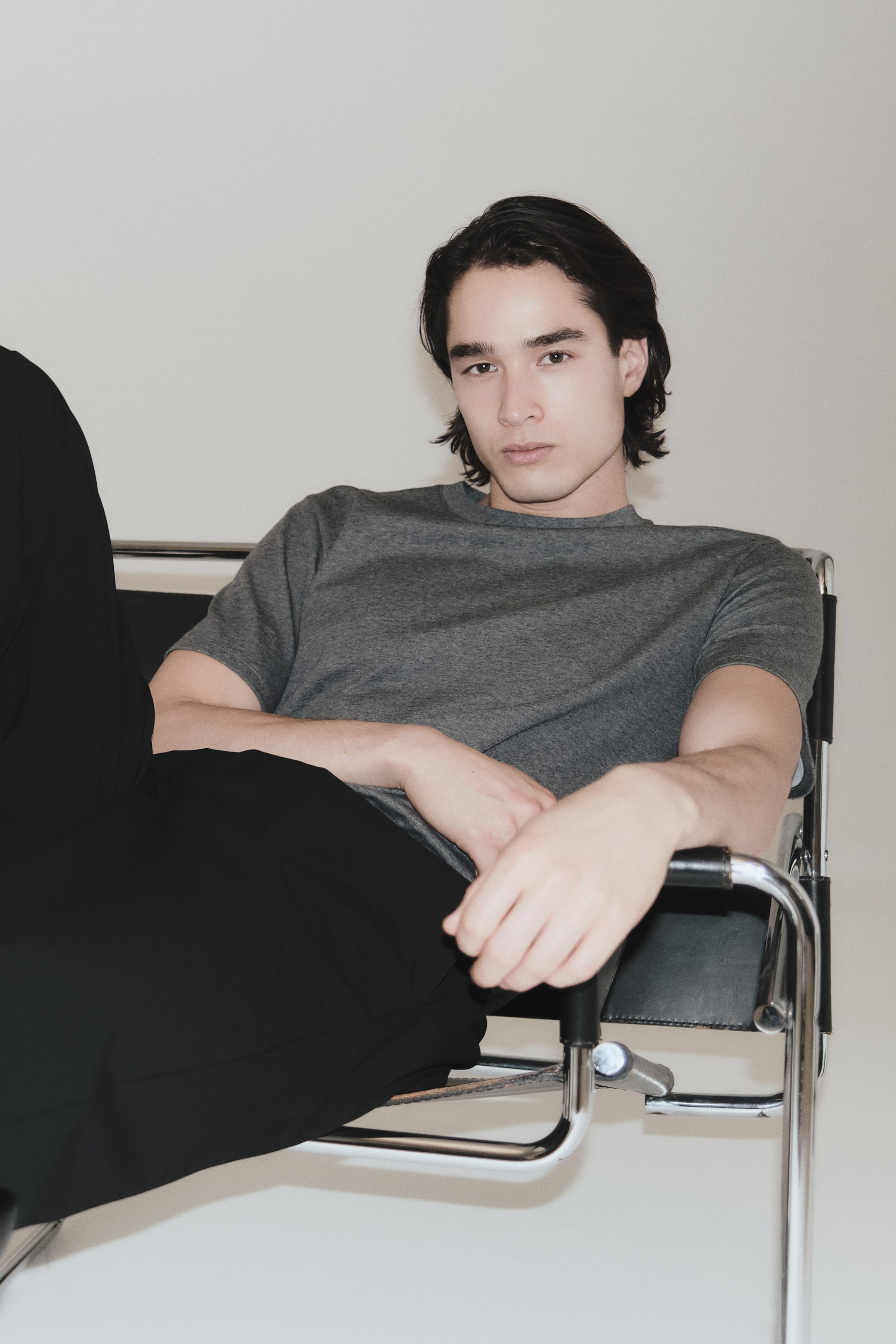 Xem ảnh lớn hơn: Một chiếc áo thun cổ tròn màu xám đang được mặc, có tay ngắn và phom dáng rộng. Nó được phối cùng quần màu đen, dáng suông rộng, rủ mượt xuống chân.