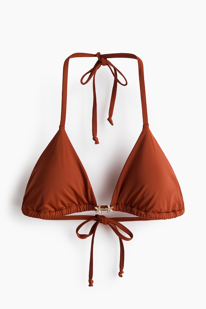 Un top de bikini triangular de color óxido presenta un cierre halter con lazada en el cuello y un cierre trasero con lazo, con dos cuentas doradas en forma de estrella de mar que conectan las copas ligeramente fruncidas. - 1